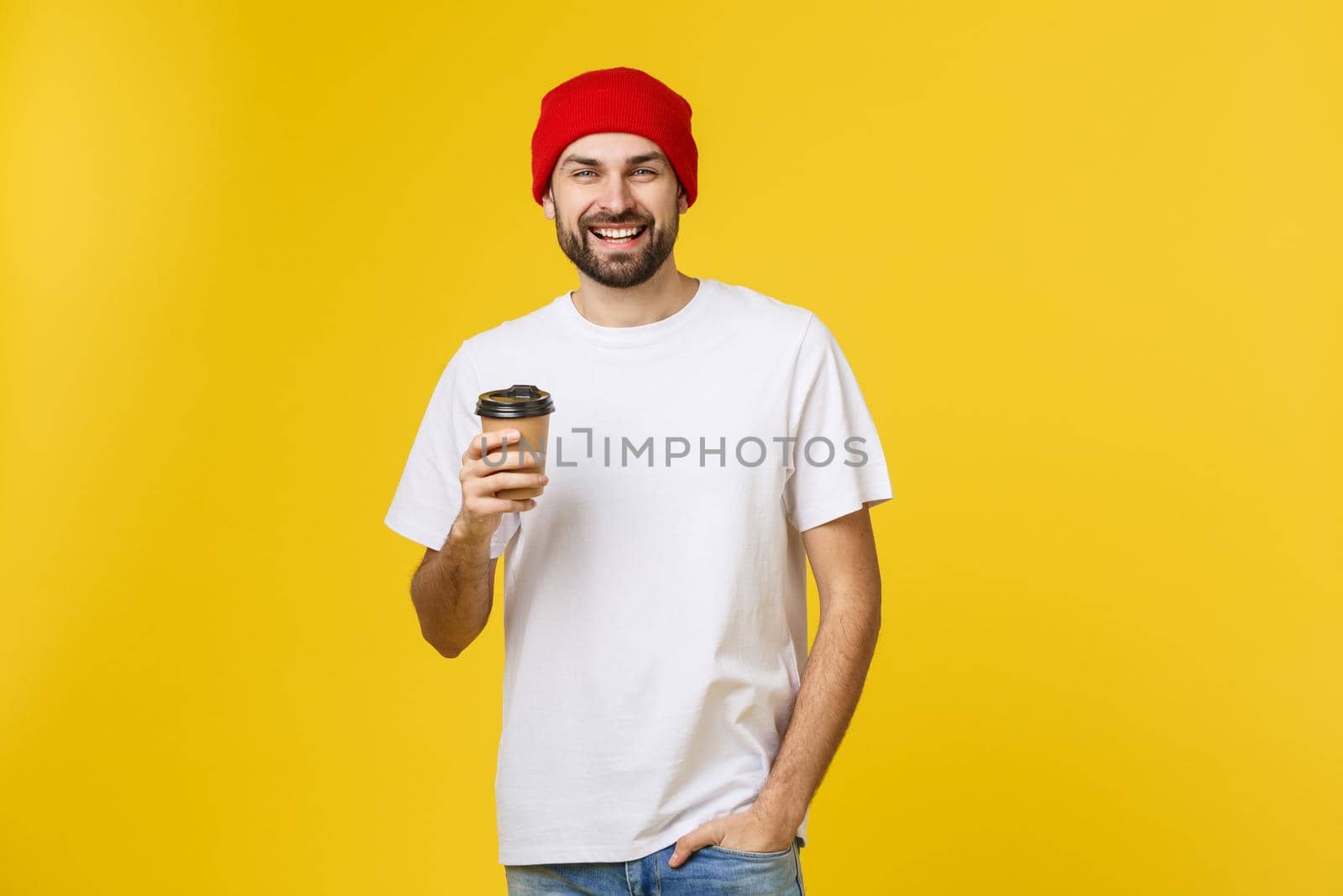 Man on isolated vibrant yellow color taking a coffee in takeaway paper cup and smiling because he will start the day well. by Benzoix
