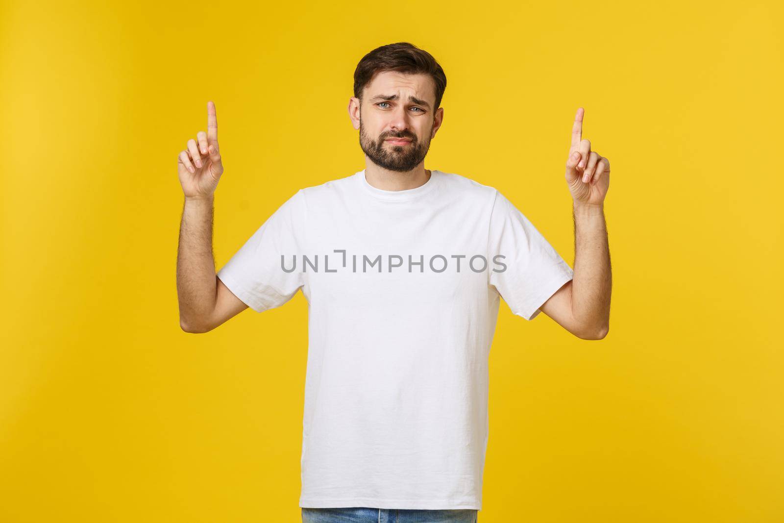 Handsome man over isolated yellow wall frustrated and pointing to the front. by Benzoix