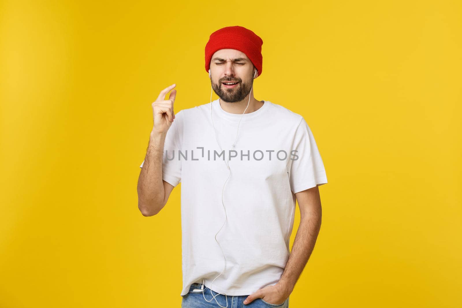 Portrait of a handsome young man dancing and listening music, isolated on yellow background.