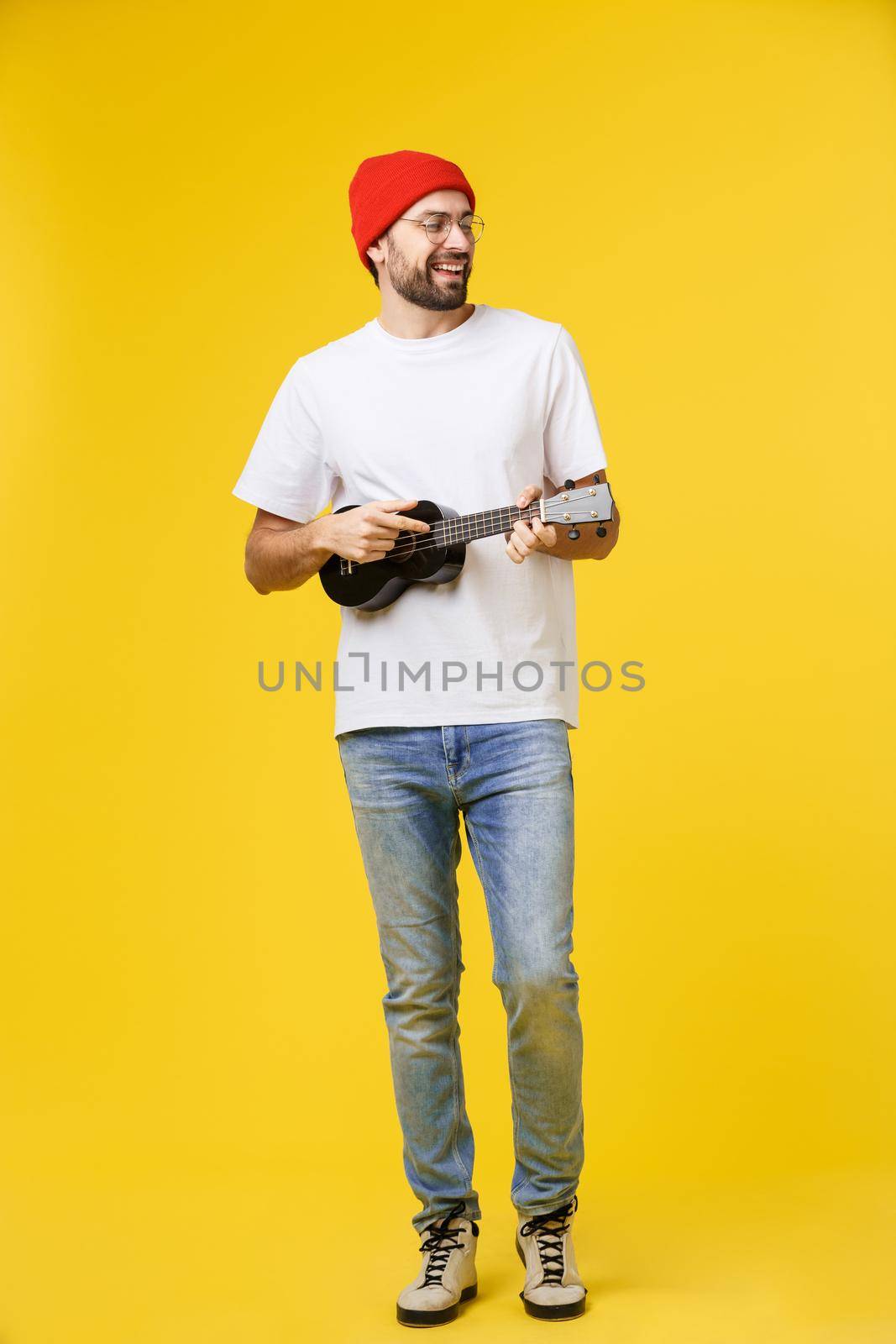 Guitarist man plays on the electric guitar with bright emotions, isolated on yellow background