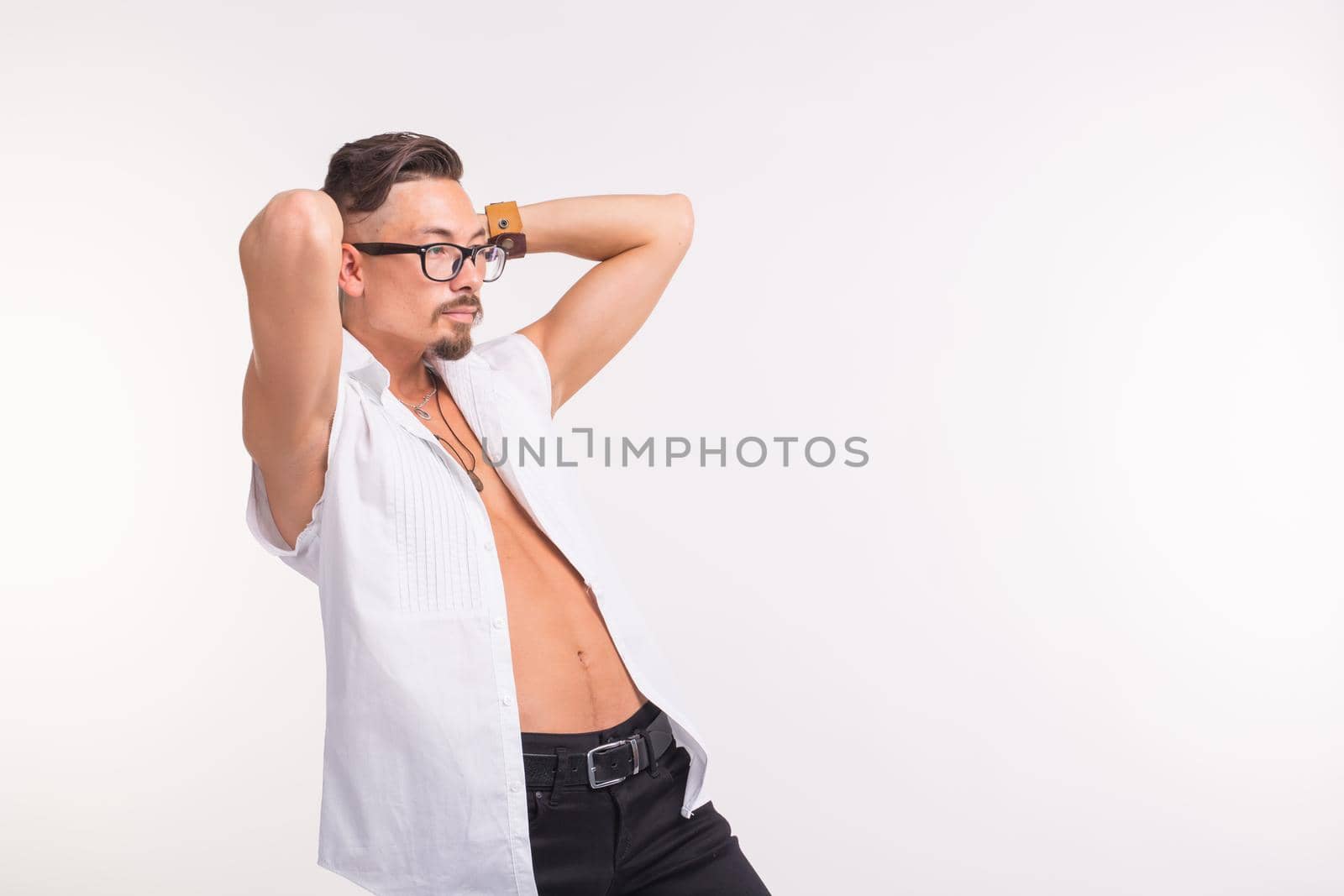 People, clothing and style concept - young handsome man posing in white shirt on white background.