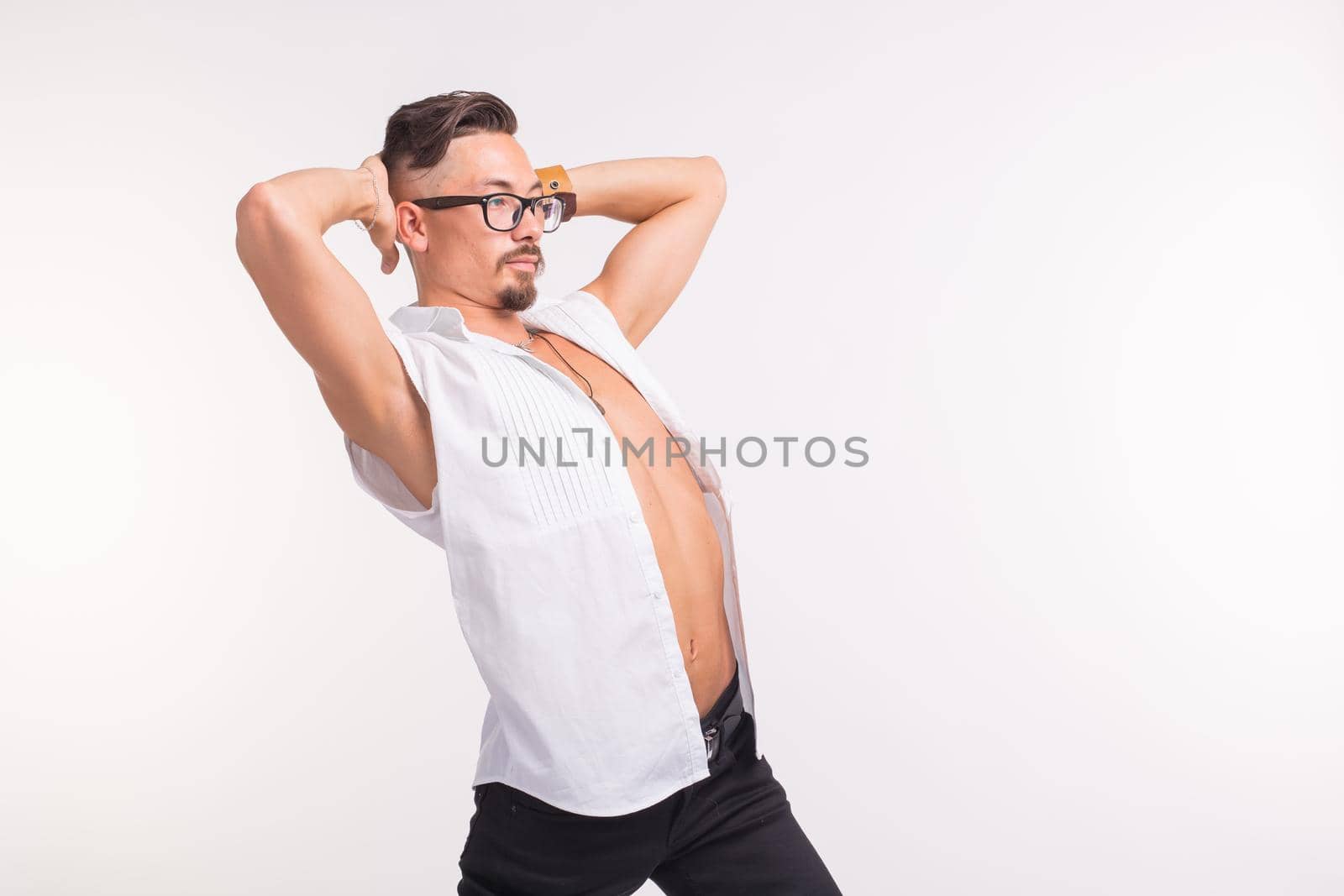 People, clothing and style concept - young handsome man posing in white shirt on white background.