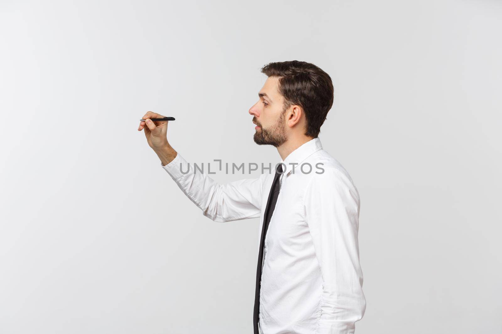 A view of a young businessman holding a pen, ready to write something, isolated on white background.