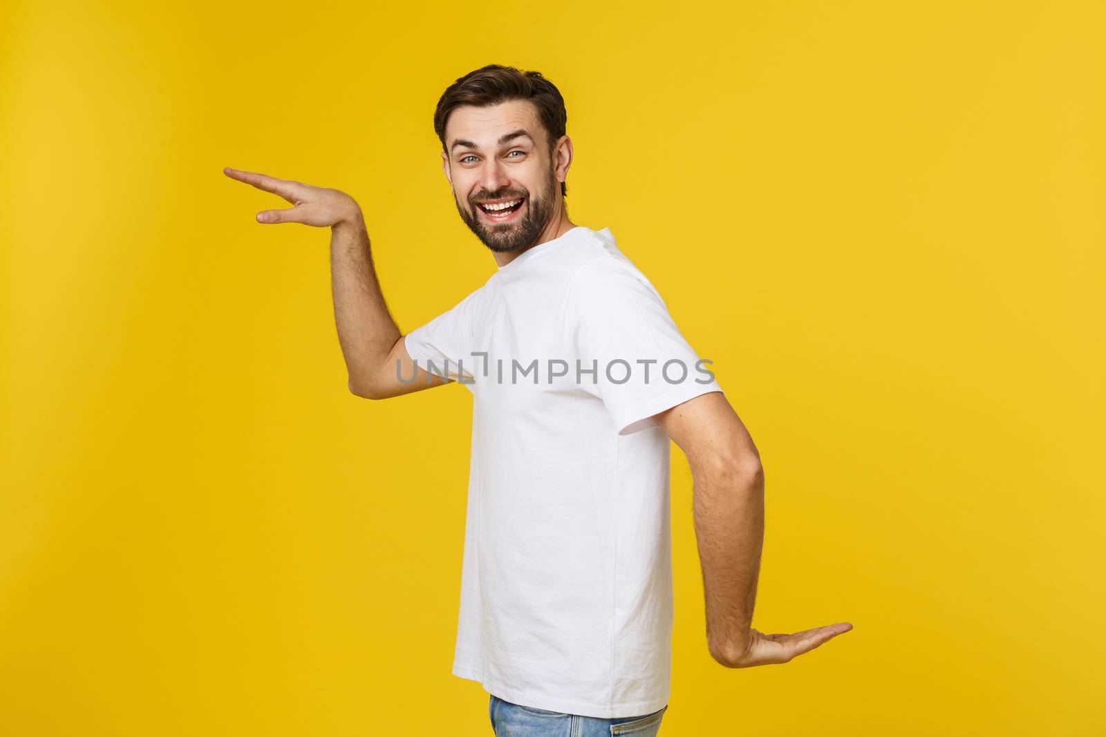 Young caucasian man isolated on yellow dancing and having fun. by Benzoix