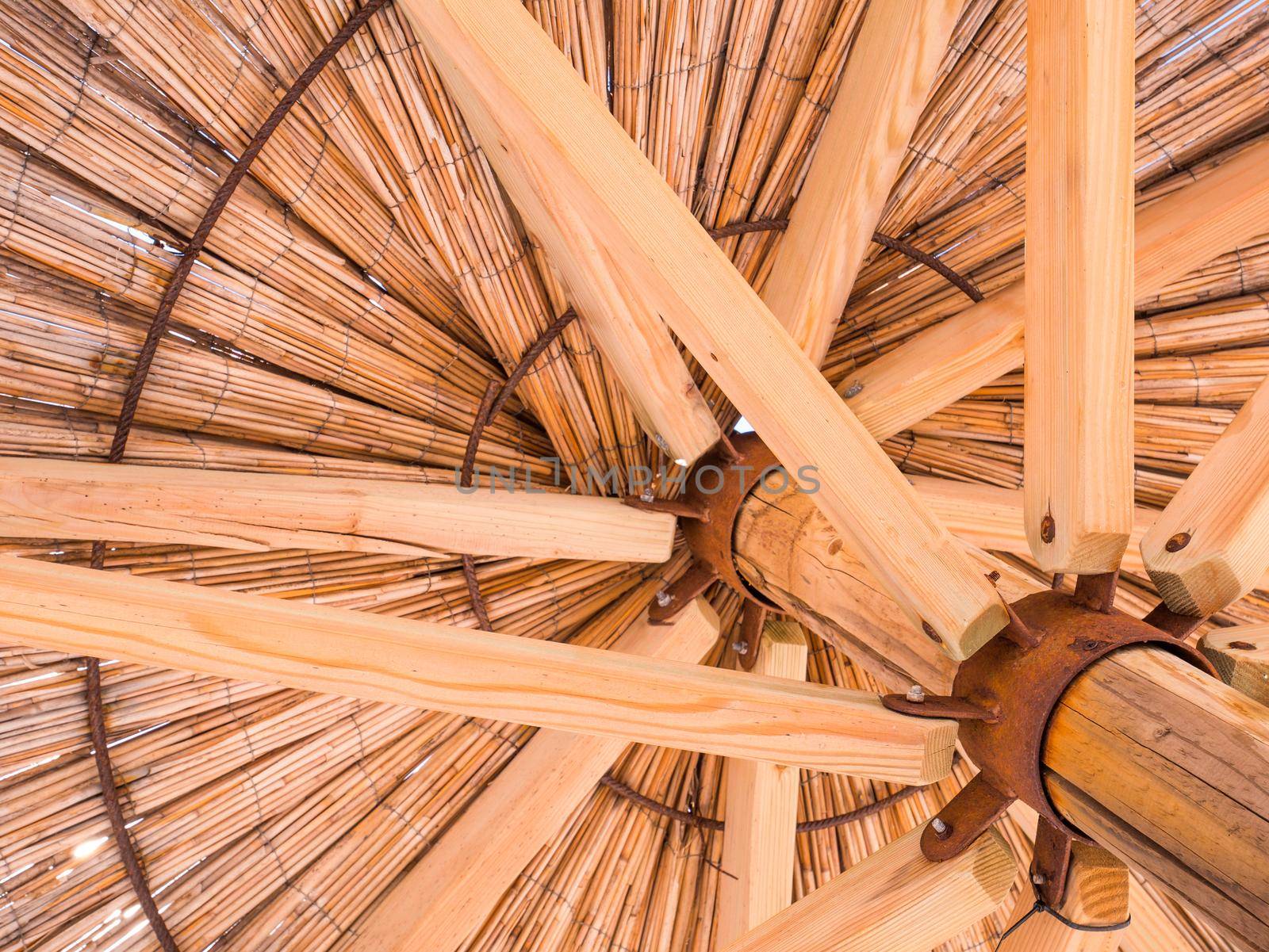 Straw beach umbrella from down side. Made of straw, wood and iron rings.