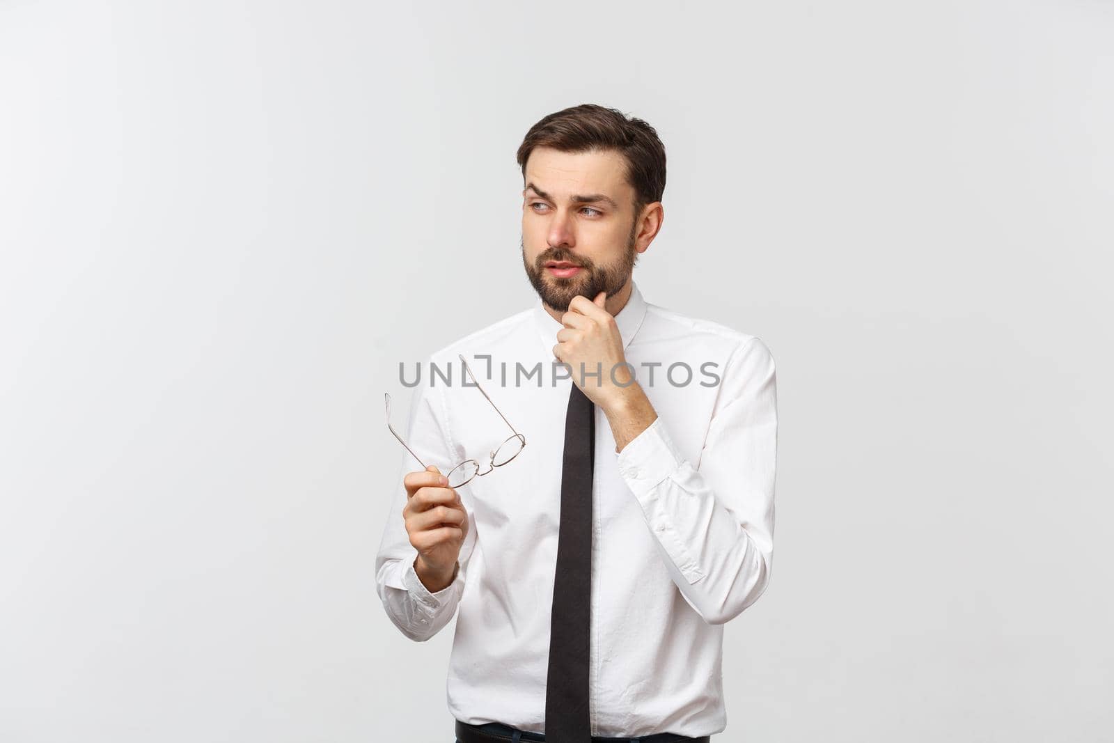 A handsome young Caucasian millennial man in glasses and a white T-shirt isolated on a gray studio background, looks at blank copy. by Benzoix