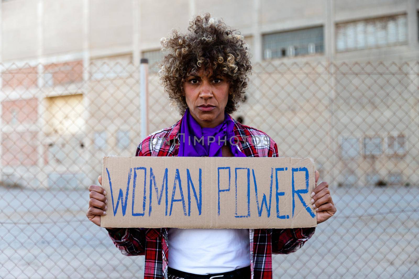 Confident African american demonstration protester looking at camera holding a woman power sign. Female empowerment concept.