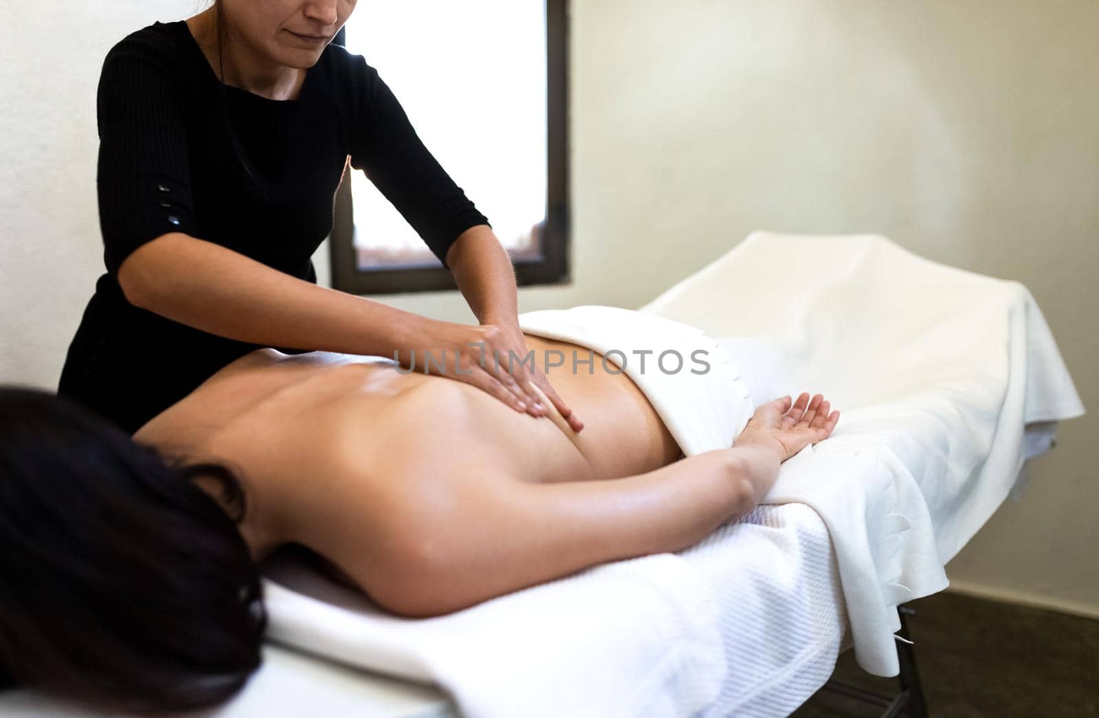 Female massage therapist giving therapeutic massage to young woman. Copy space. by Hoverstock