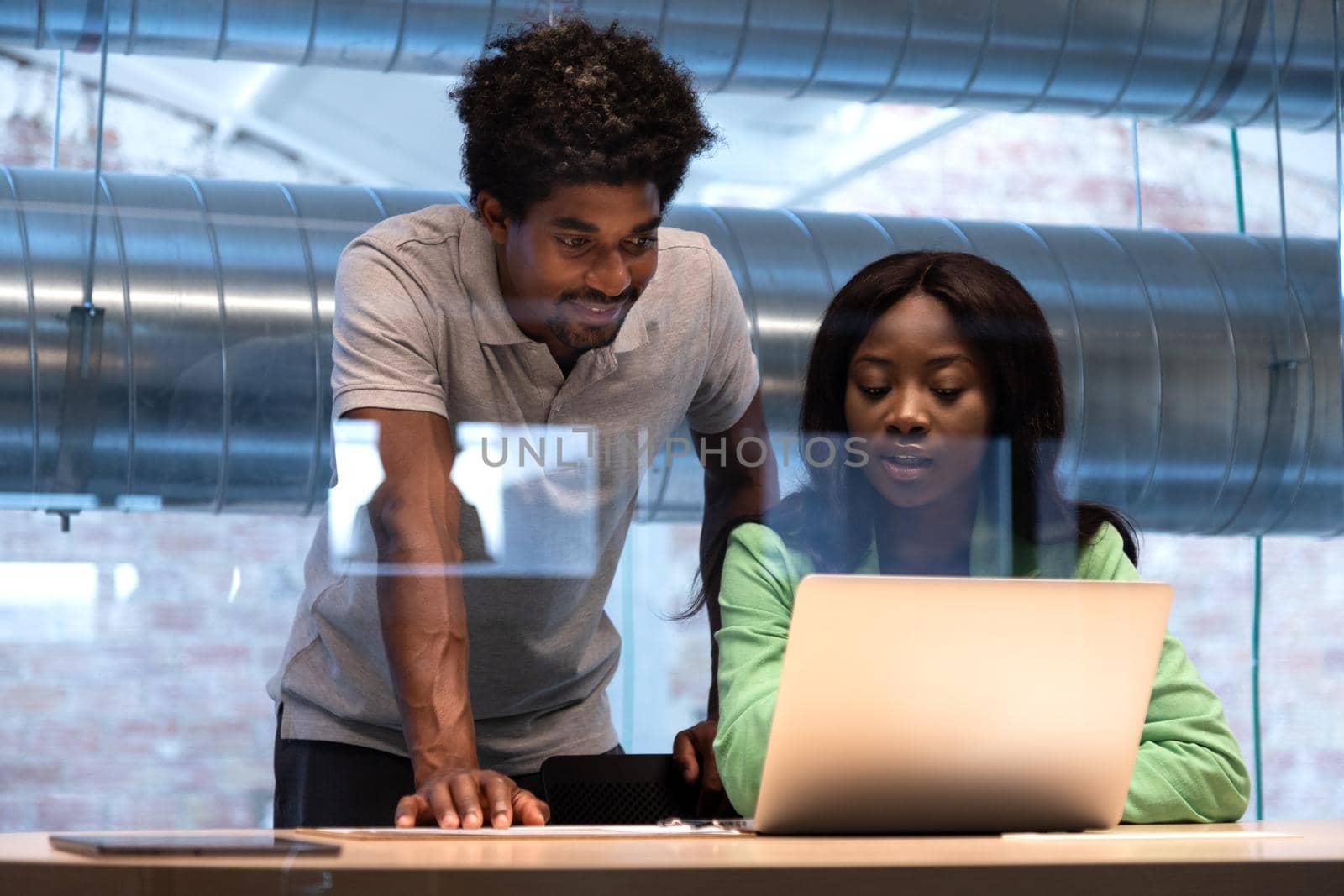 Two african american coworkers analyse reports together at the office using laptop. Business and technology concept.