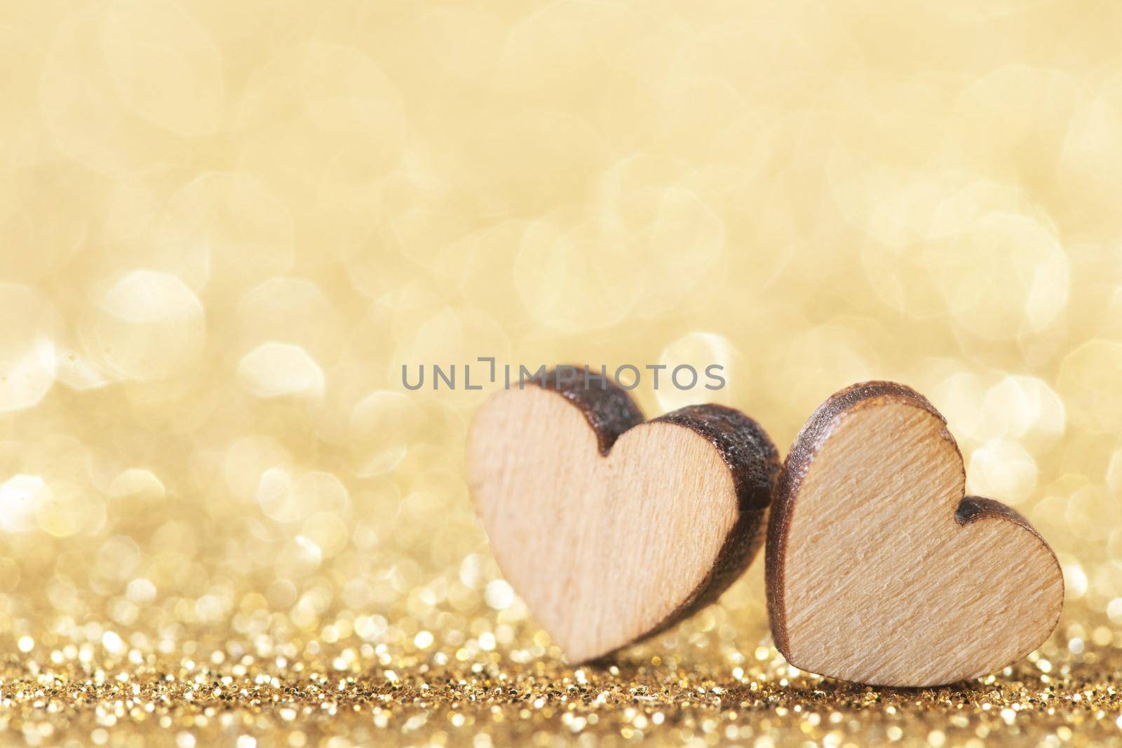 Two small handmade wooden hearts on bright golden lights bokeh background Valentines day card with copy space