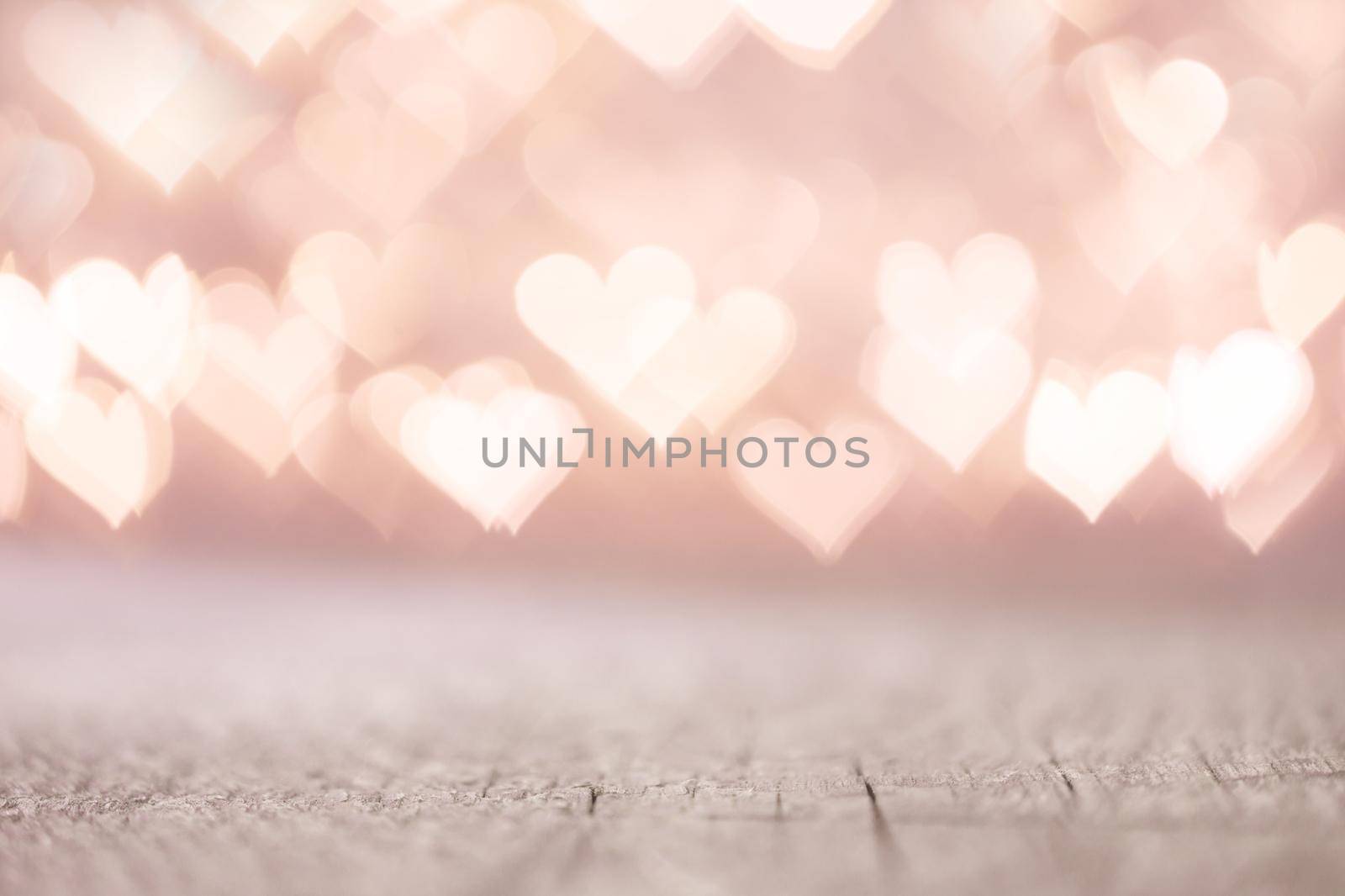Valentine's Day bokeh pink lights hearts over wooden table background woth copy space for product
