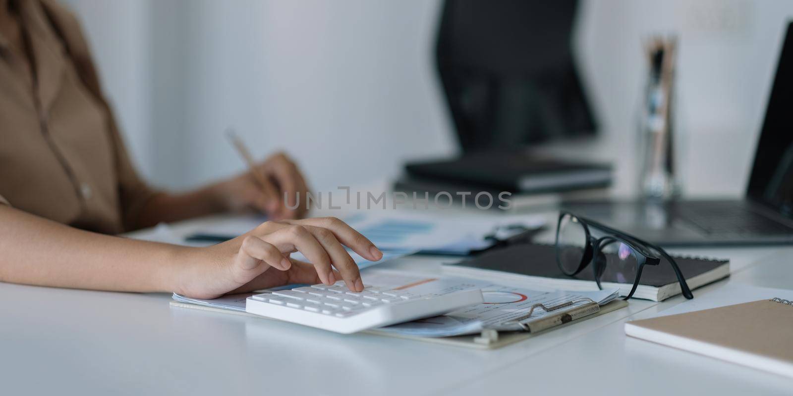 Financial woman use laptop and calculator to analyze marketing strategies and real estate data to reduce company taxes for their customers, Accounting and Tax concept.