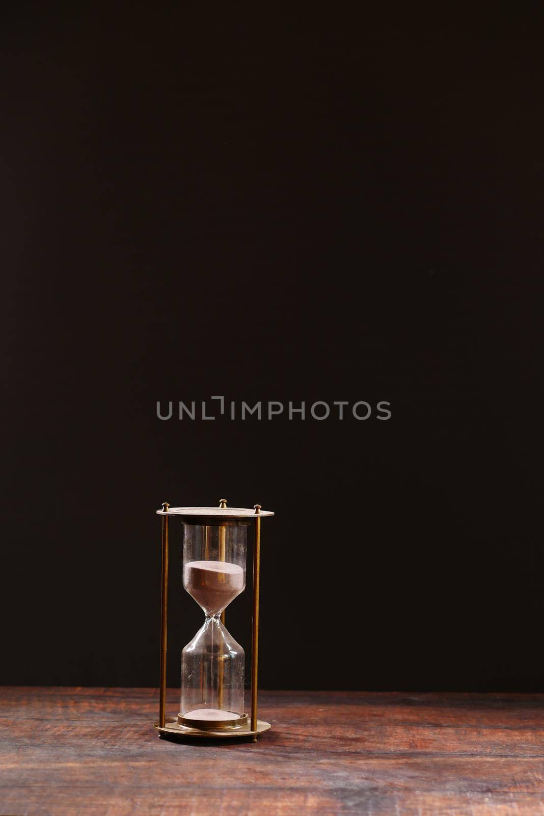 hourglass on table, sand flowing through the bulb of sandglass by towfiq007