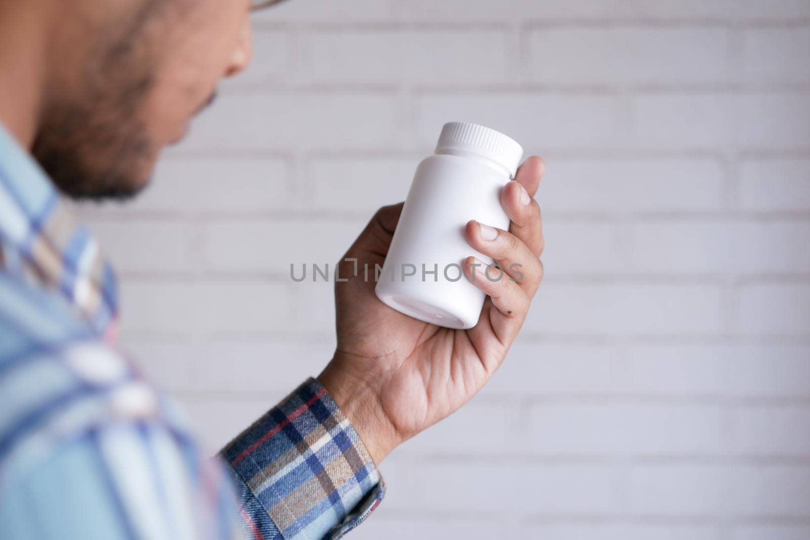 young man hand holding medicine pill container .