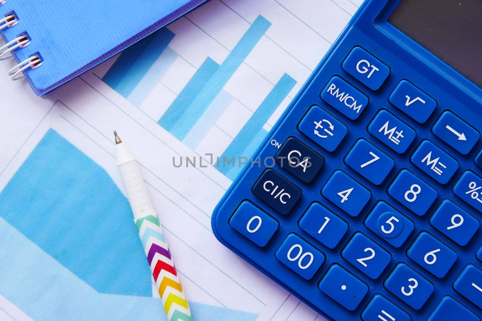 Close up of blue calculator and financial chart on table