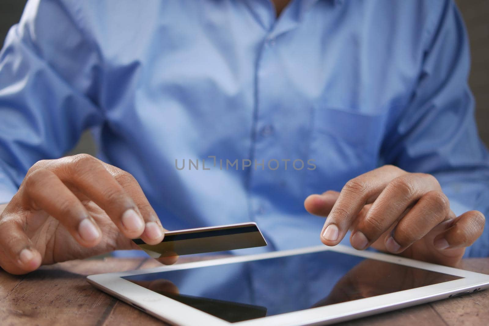 young man putting credit card detail on digital tablet ,