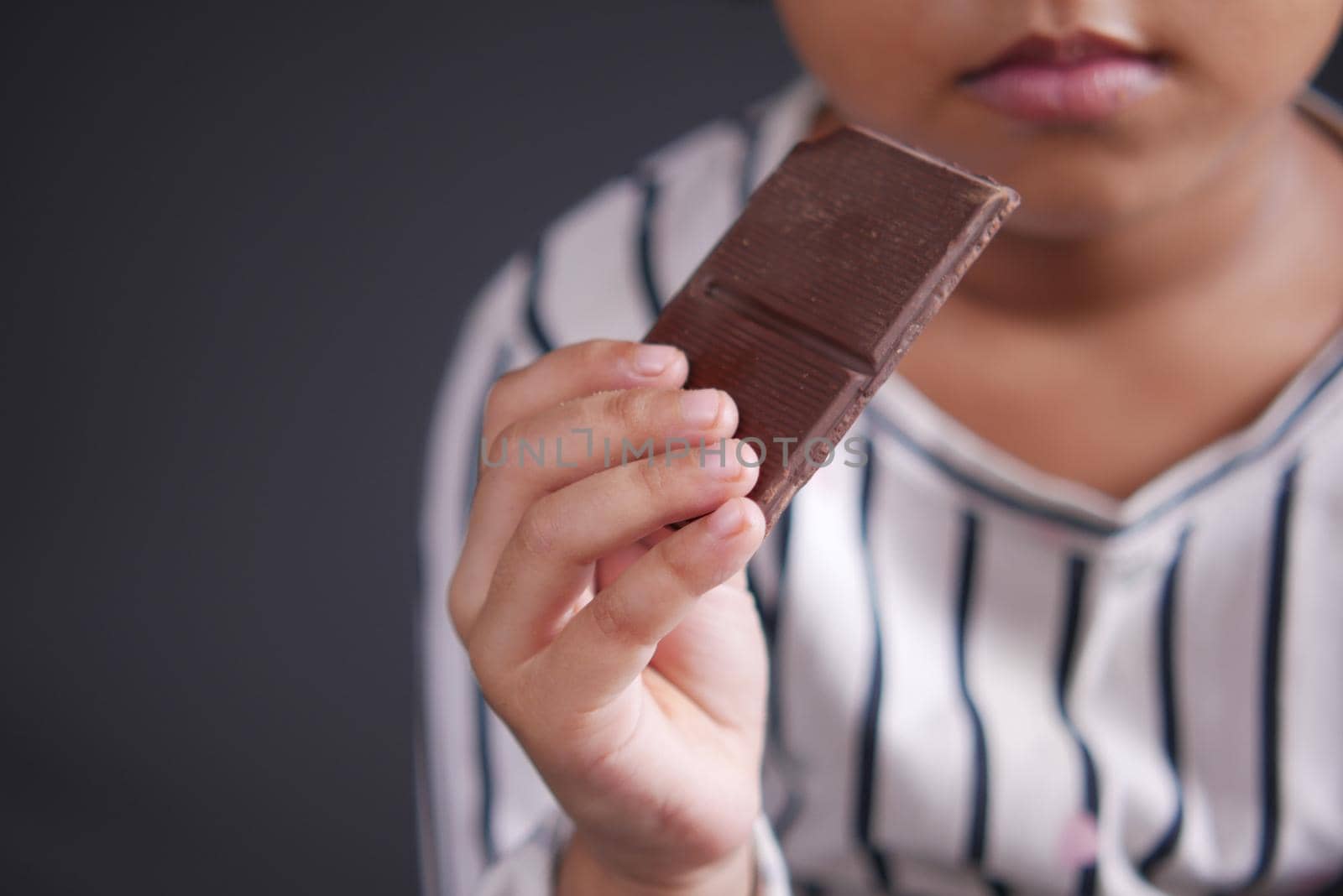 child girl hand pick dark chocolate against gray background ,