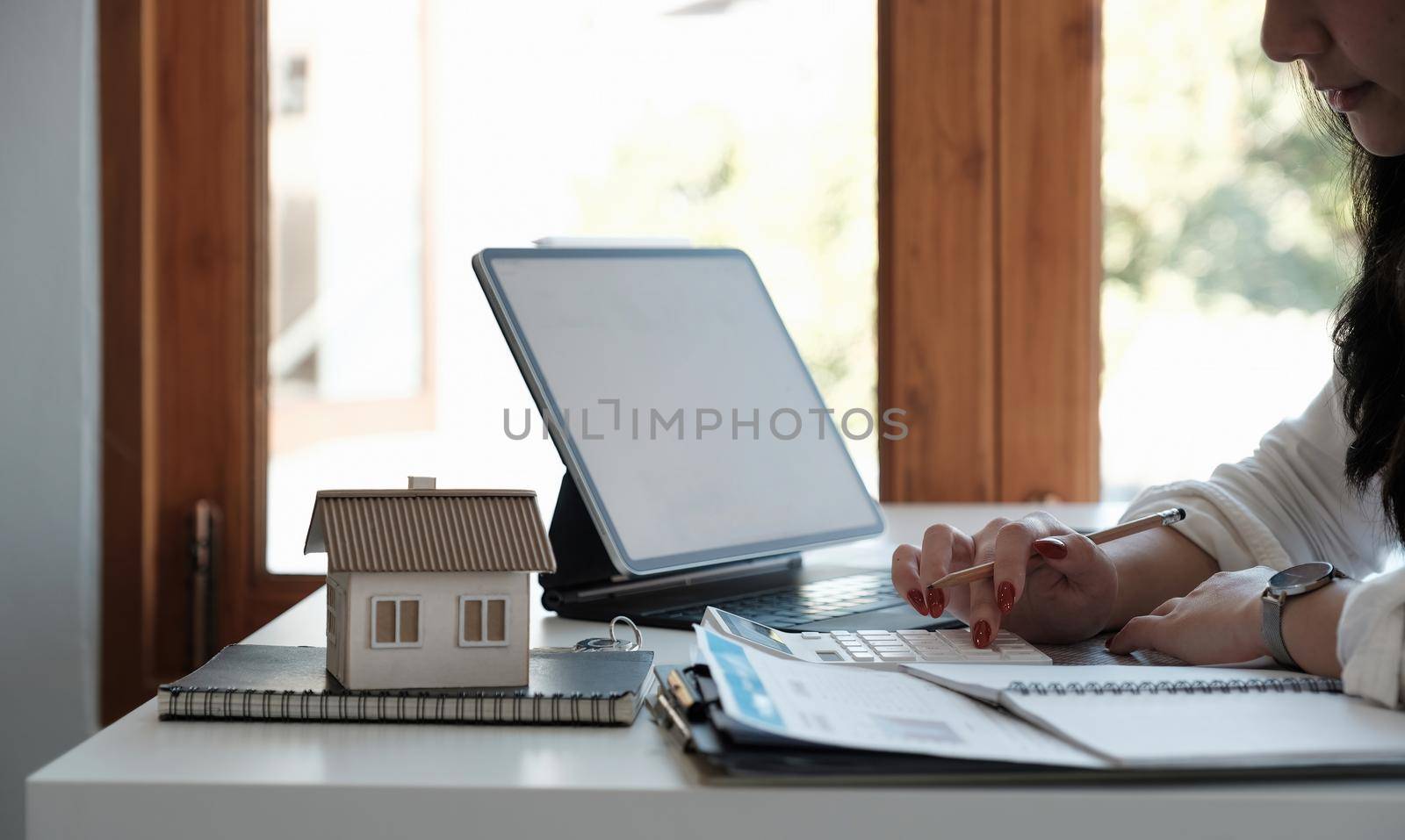 Close up hand of Business asian woman using calculating interest, taxes and profits to invest in real estate and home buying