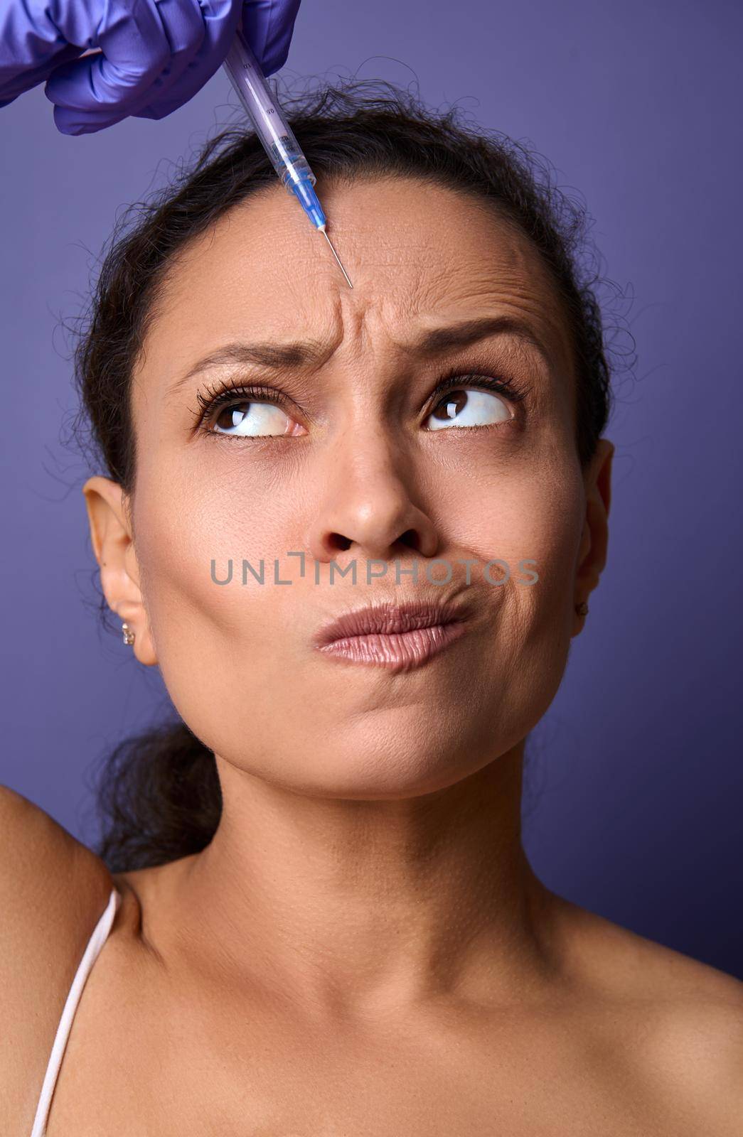 Charming middle-aged woman receiving a beauty injection of botulinum toxin into her forehead area to rejuvenate and reduce the signs of ageing and the appearance of the first wrinkles on her face