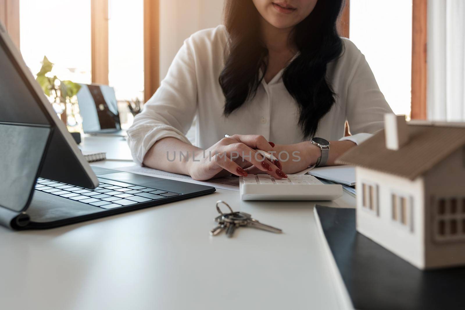 Close up hand of Business asian woman using calculating interest, taxes and profits to invest in real estate and home buying