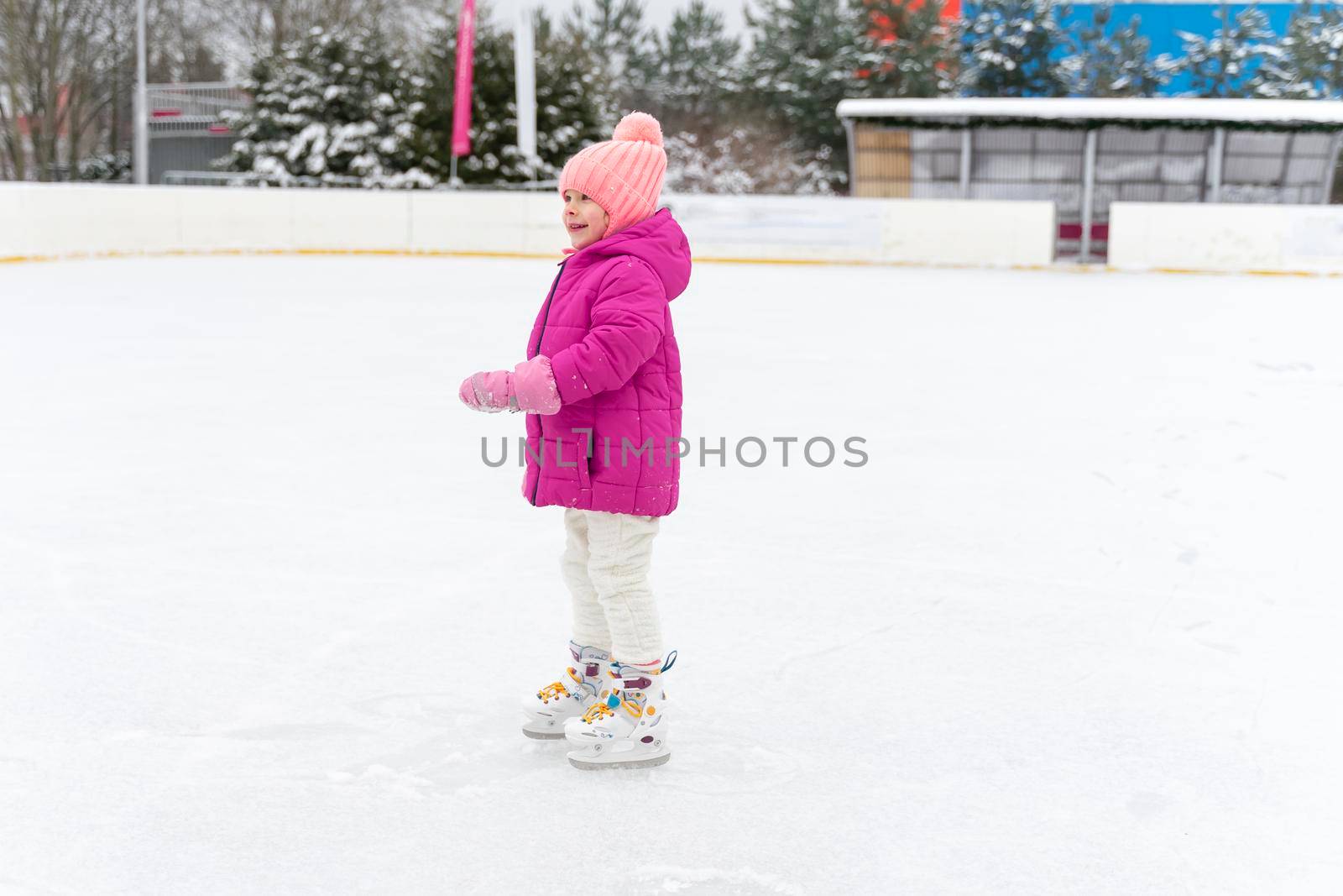 Adorable kid girl skating on ice rink