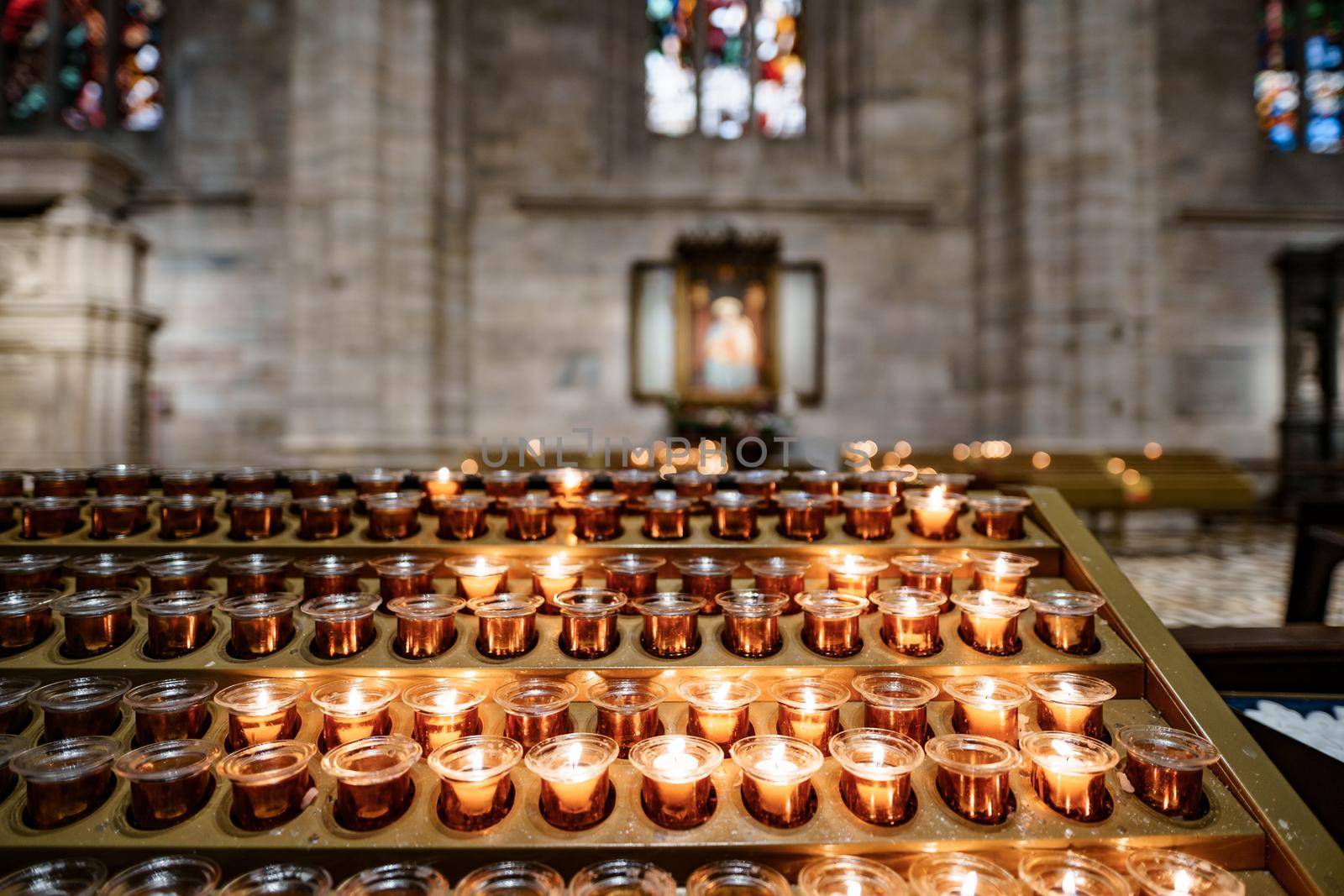 Votive candles are burning on a stand in the Duomo Cathedral. Close-up. High quality photo