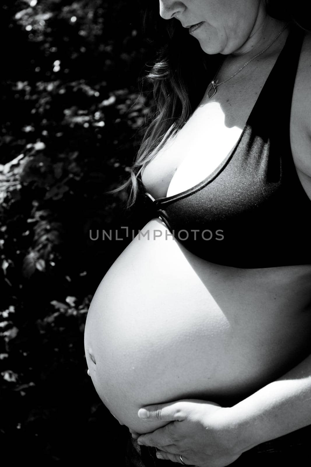 Seven month pregnant woman in a park dressed in jeans