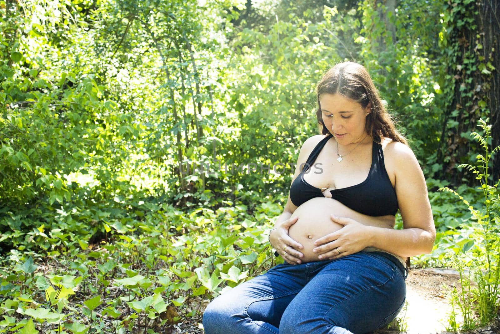Seven month pregnant woman in a park dressed in jeans