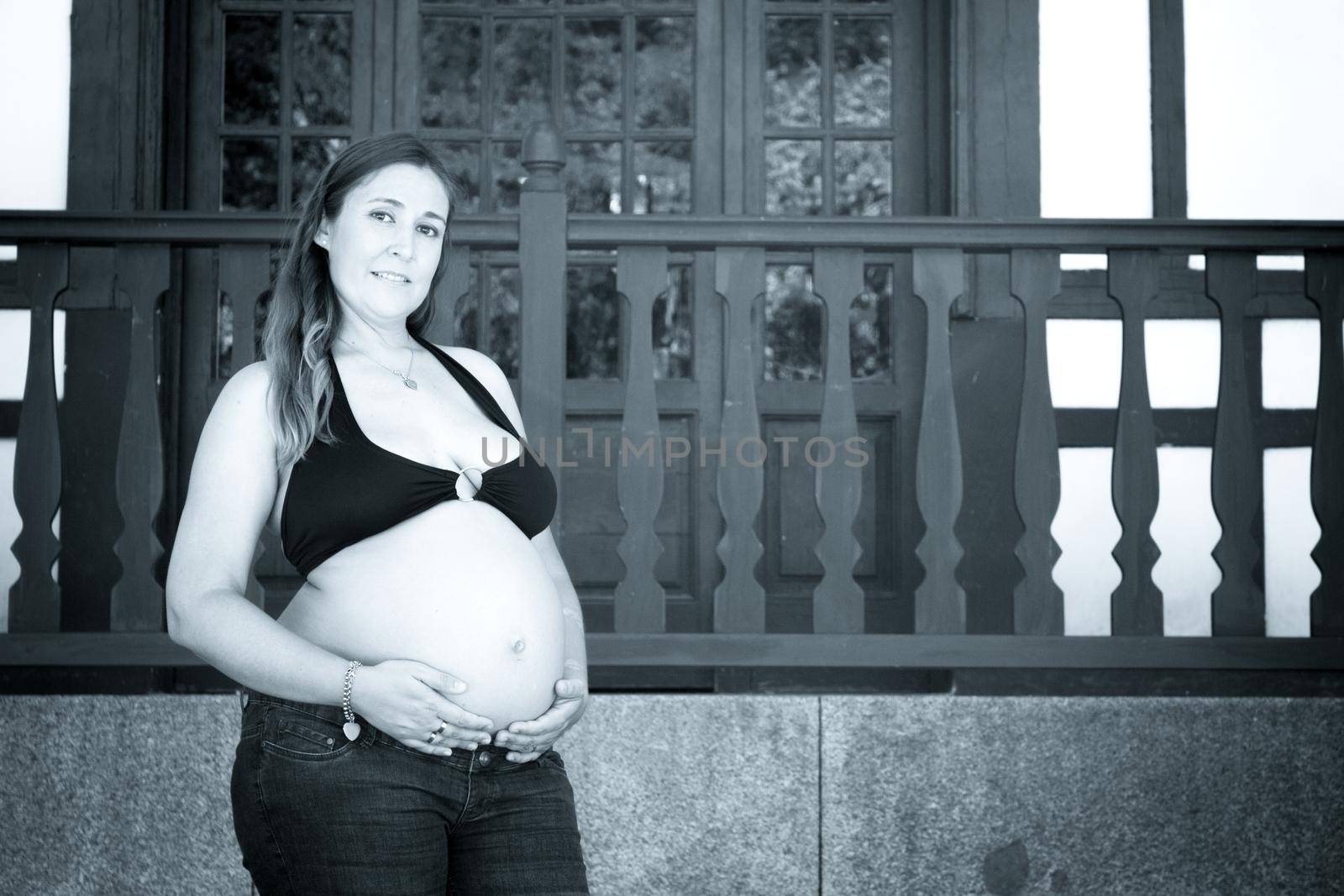 Seven months pregnant young woman dressed in black bikini and jeans