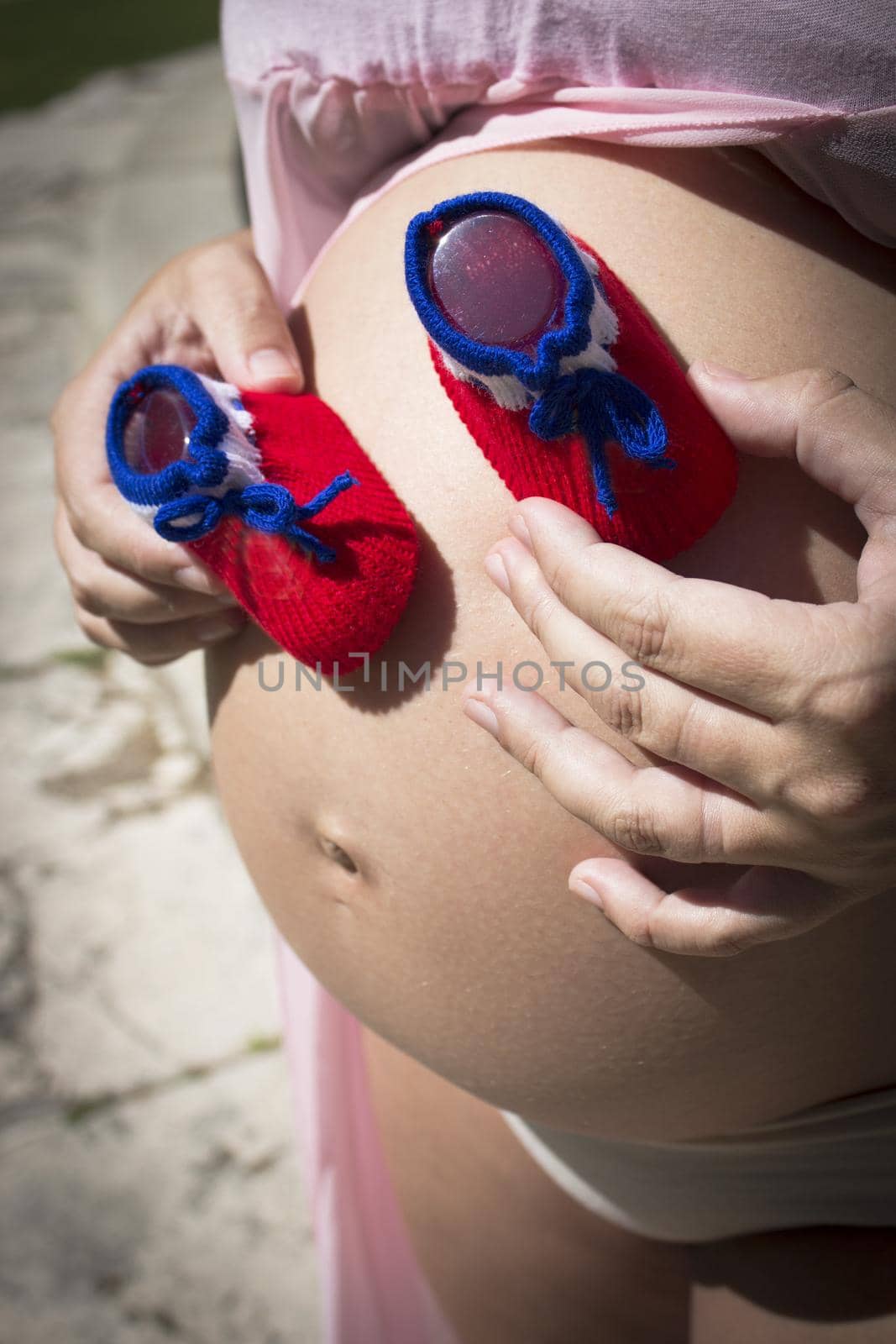 Seven months pregnant woman with red and blue booties  by GemaIbarra