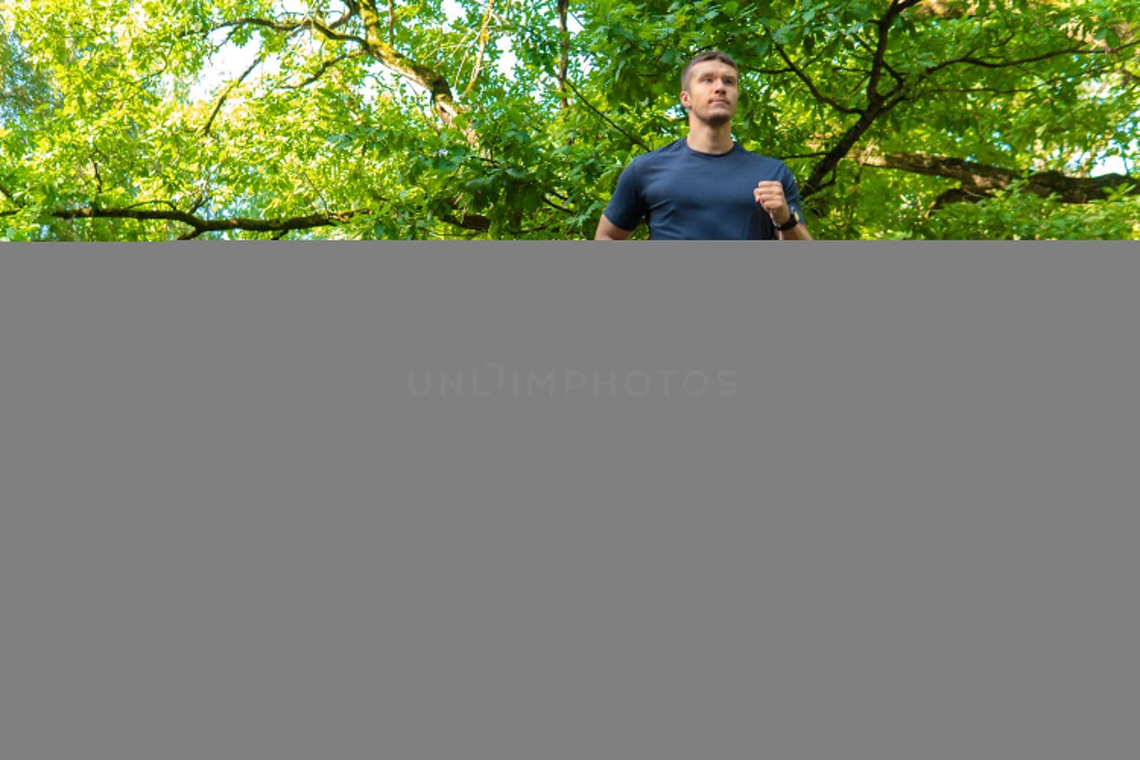 A man athlete runs in the park outdoors, around the forest, oak trees green grass young enduring athletic athlete sport nature, fitness recreation marathon, woods stretching stretches by 89167702191