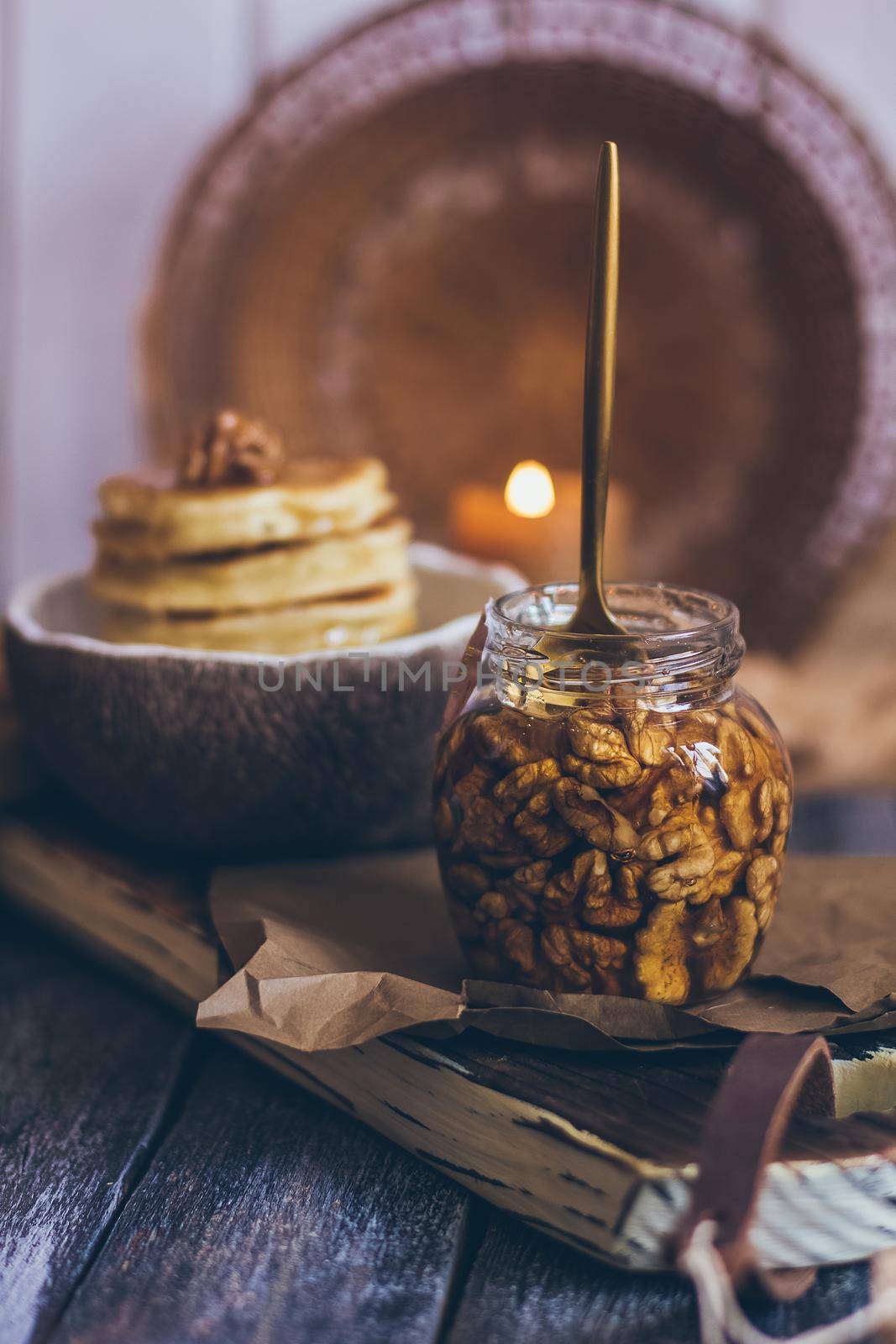 A glass jar of honey with nuts on wooden background.