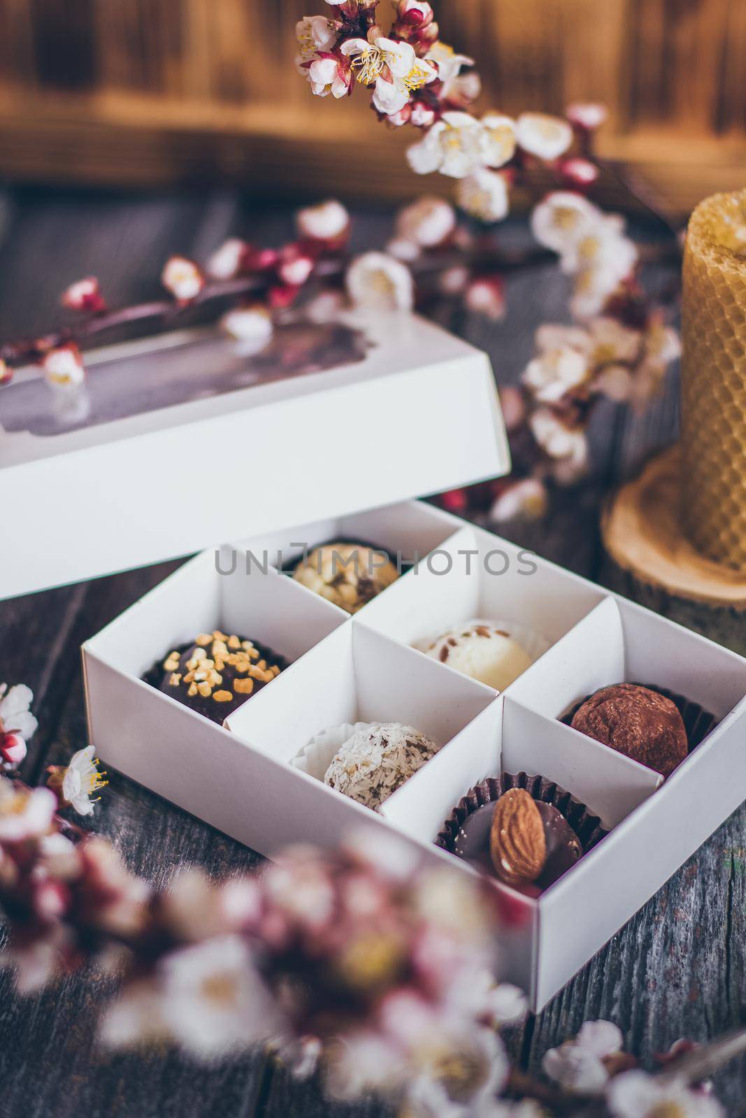 Spring collection of handmade chocolate bonbons candies and cherry flowers decoration on rustic wooden background by mmp1206