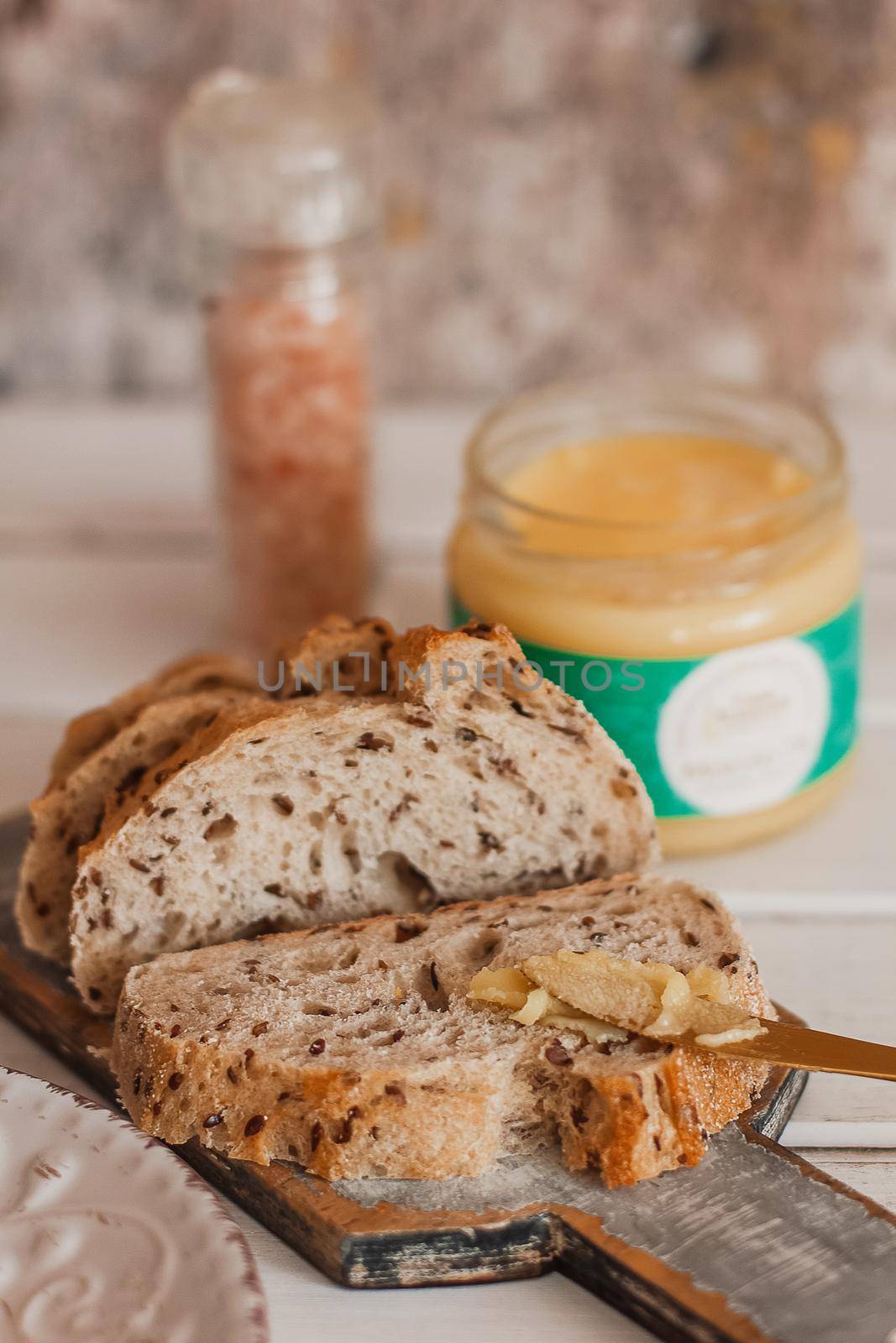 Ghee butter in glass jar and sliced bread on table. Healthy eating, breakfast.