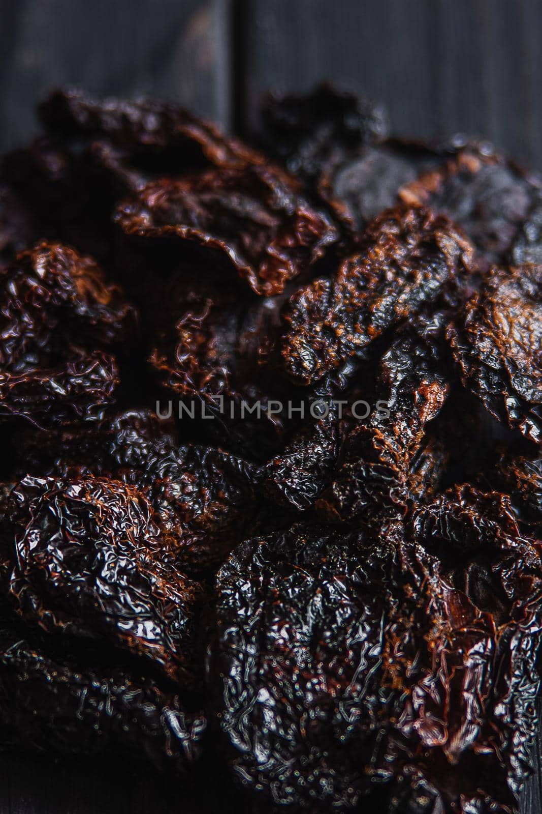 Homemade sun-dried red tomato slices on dark background. Cooking process traditional Italian Mediterranean cuisine