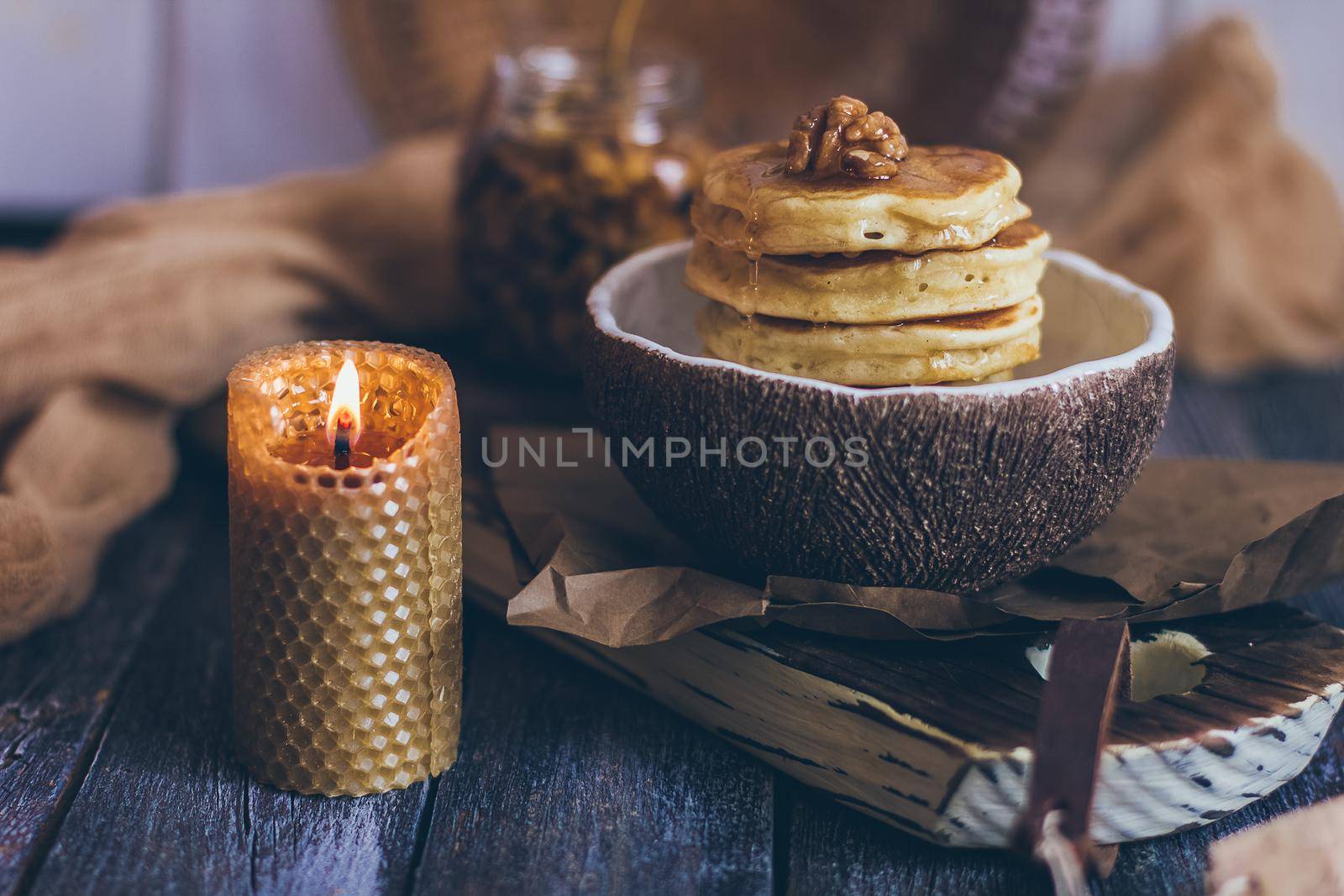 Stack of delicious pancakes with honey, nuts on wooden background.