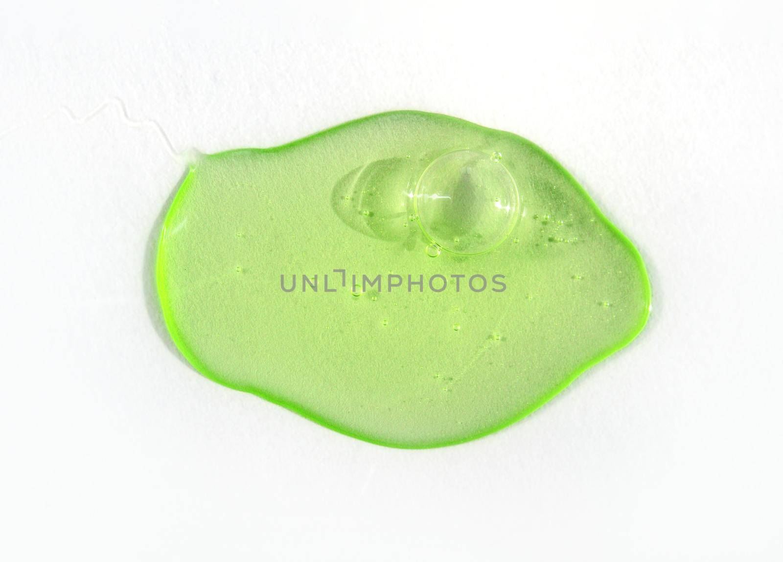 A drop of green hyaluronic acid on white background. Cosmetics and healthcare concept closeup. Dose of serum or retinol with air bubbles. Top view. Luxury gel or beauty product presentation, macro