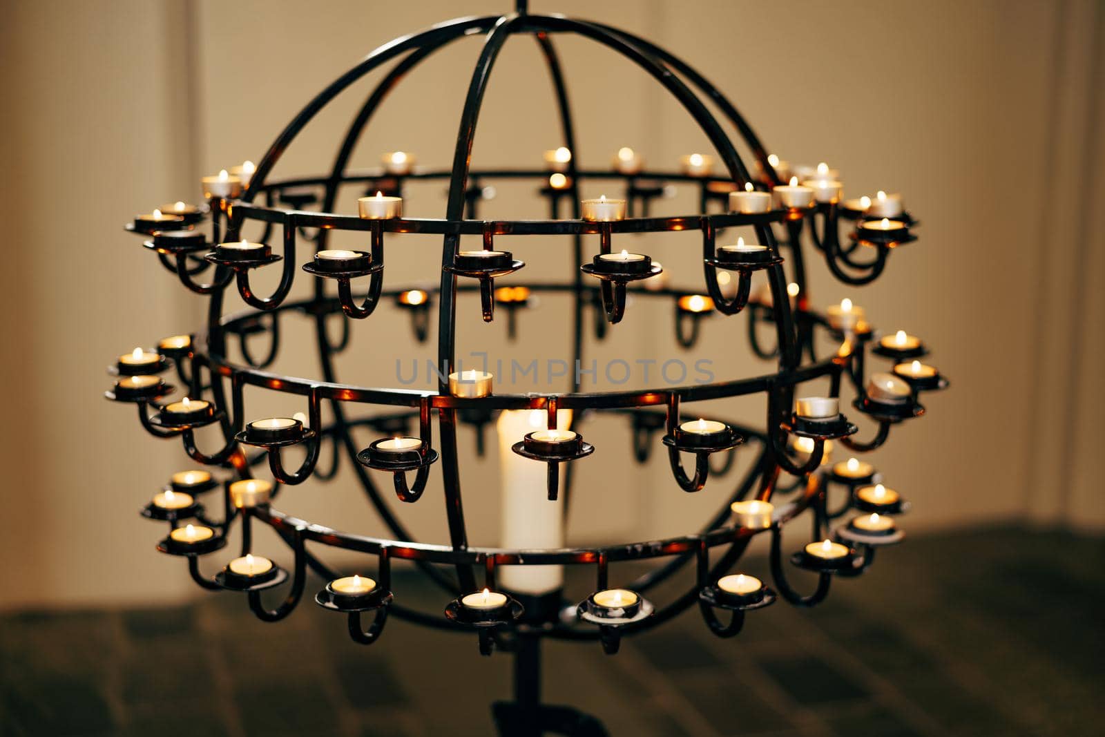 Votive candles stand on a ball-shaped stand in a church. High quality photo