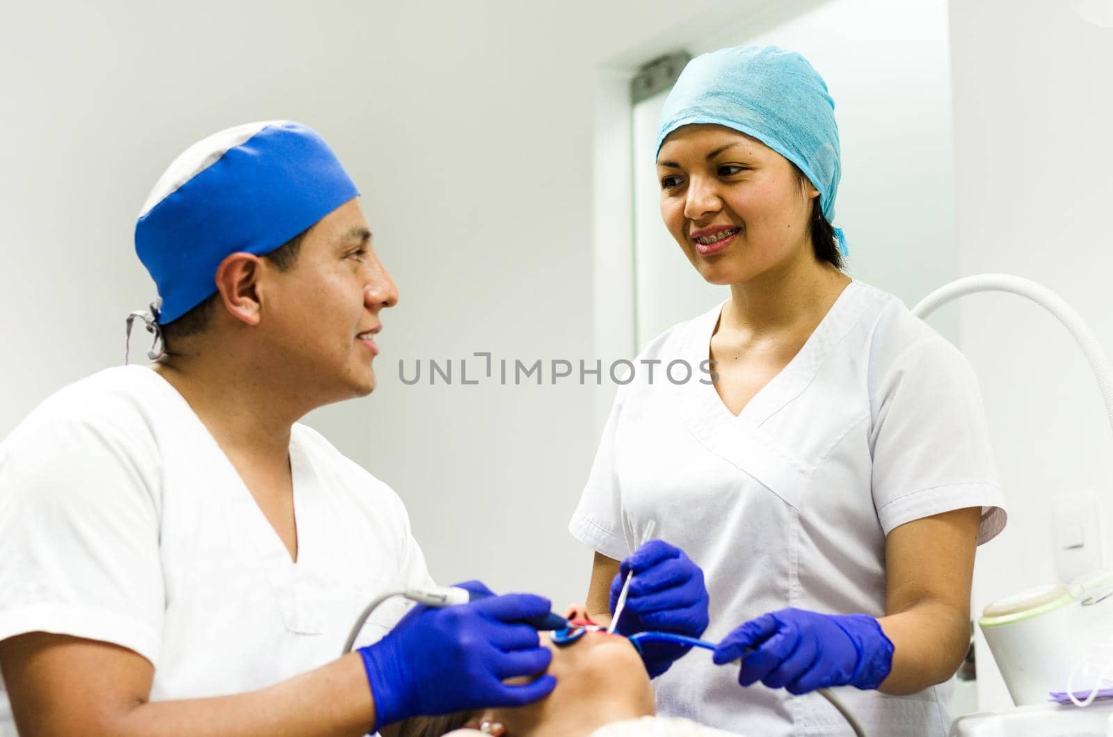 Dentists with patient in clinic smiling by Peruphotoart