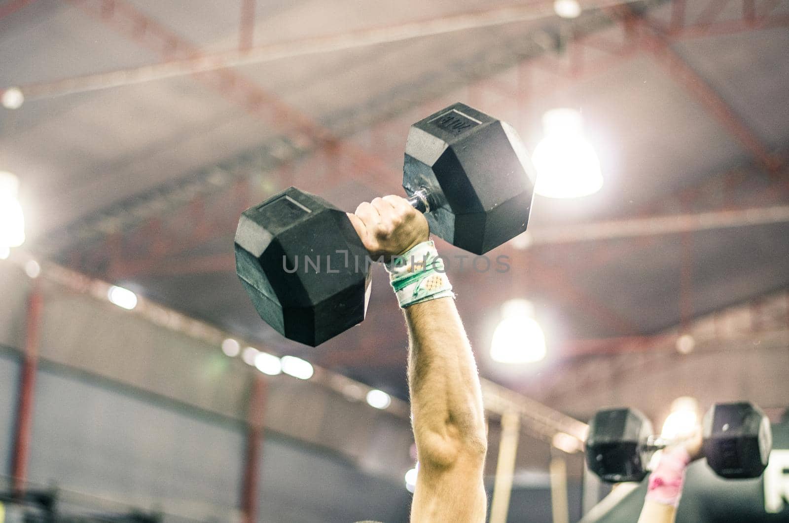 The hand of a muscular man lifting a dumbbell in the gym