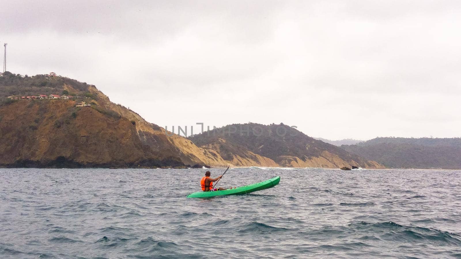 Man paddles a kayak over the sea of Montanita beach in Ecuador