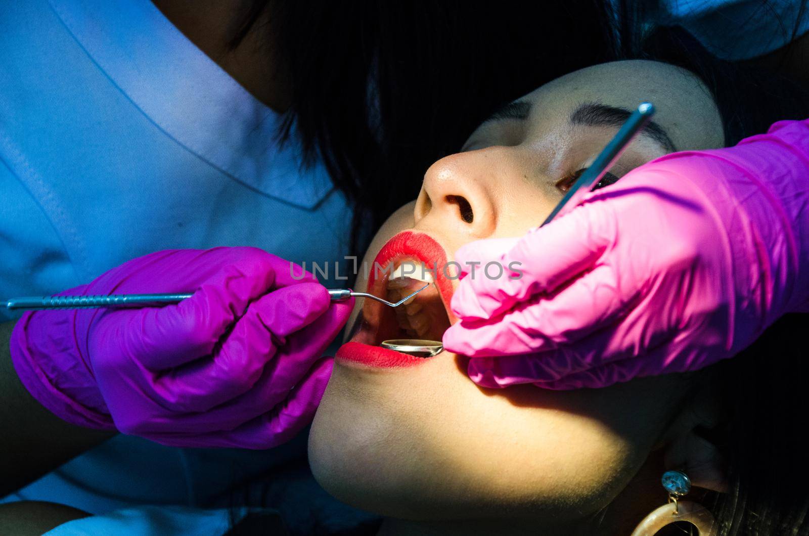 Young female patient takes a dental attendance in the dentist's office. by Peruphotoart