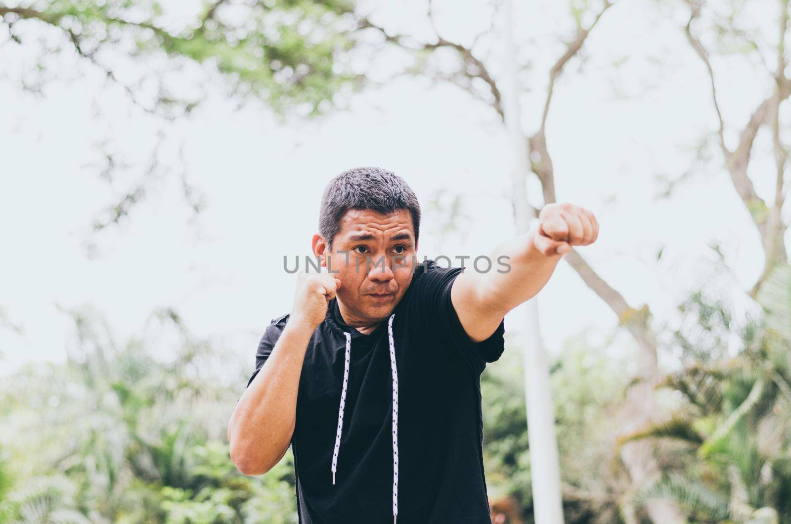 Photo of young handsome sporty fighter training outdoors in the park