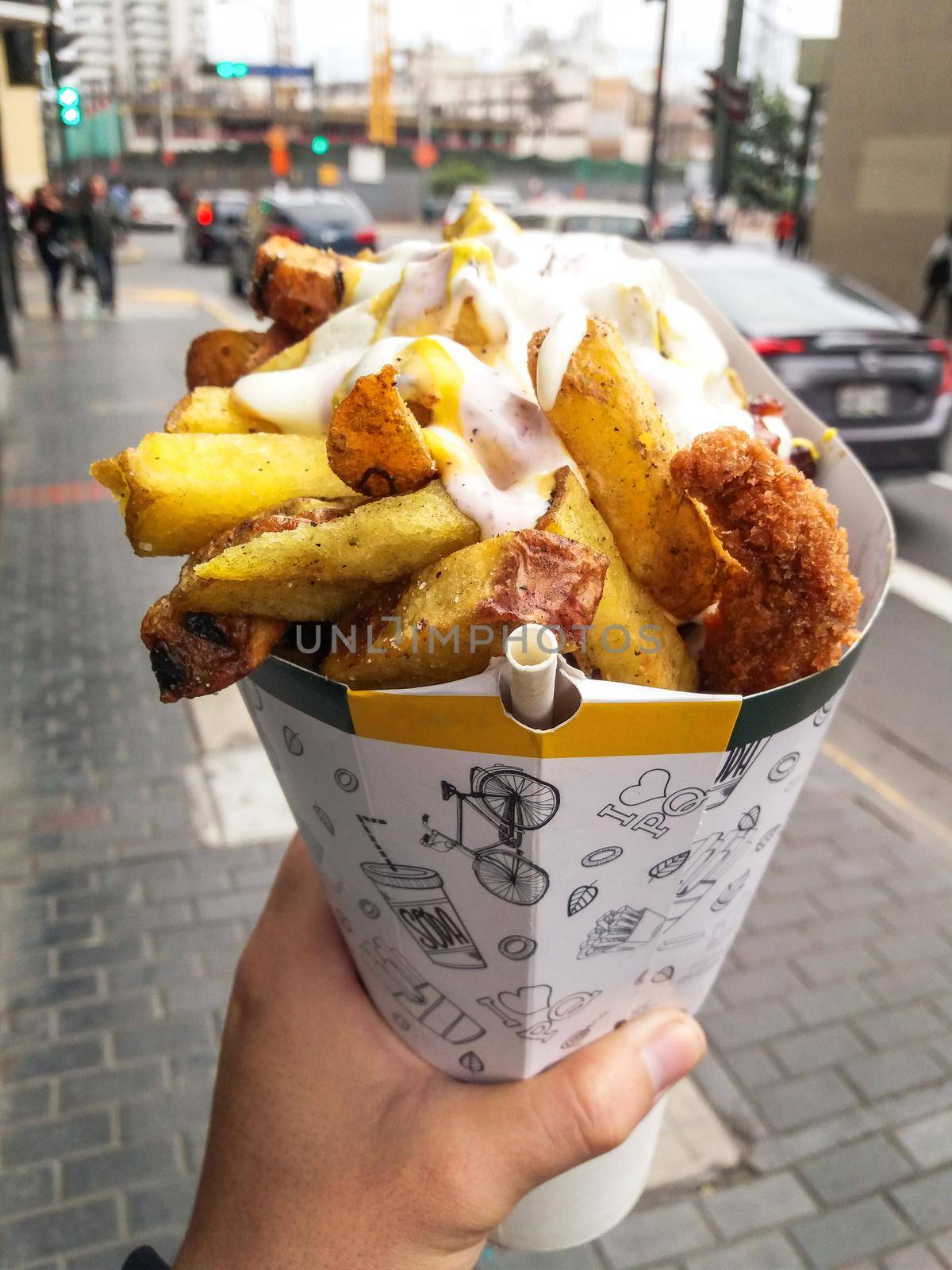 Fast street food, french fries and fried chicken with mayonnaise among other creams in a cone by Peruphotoart