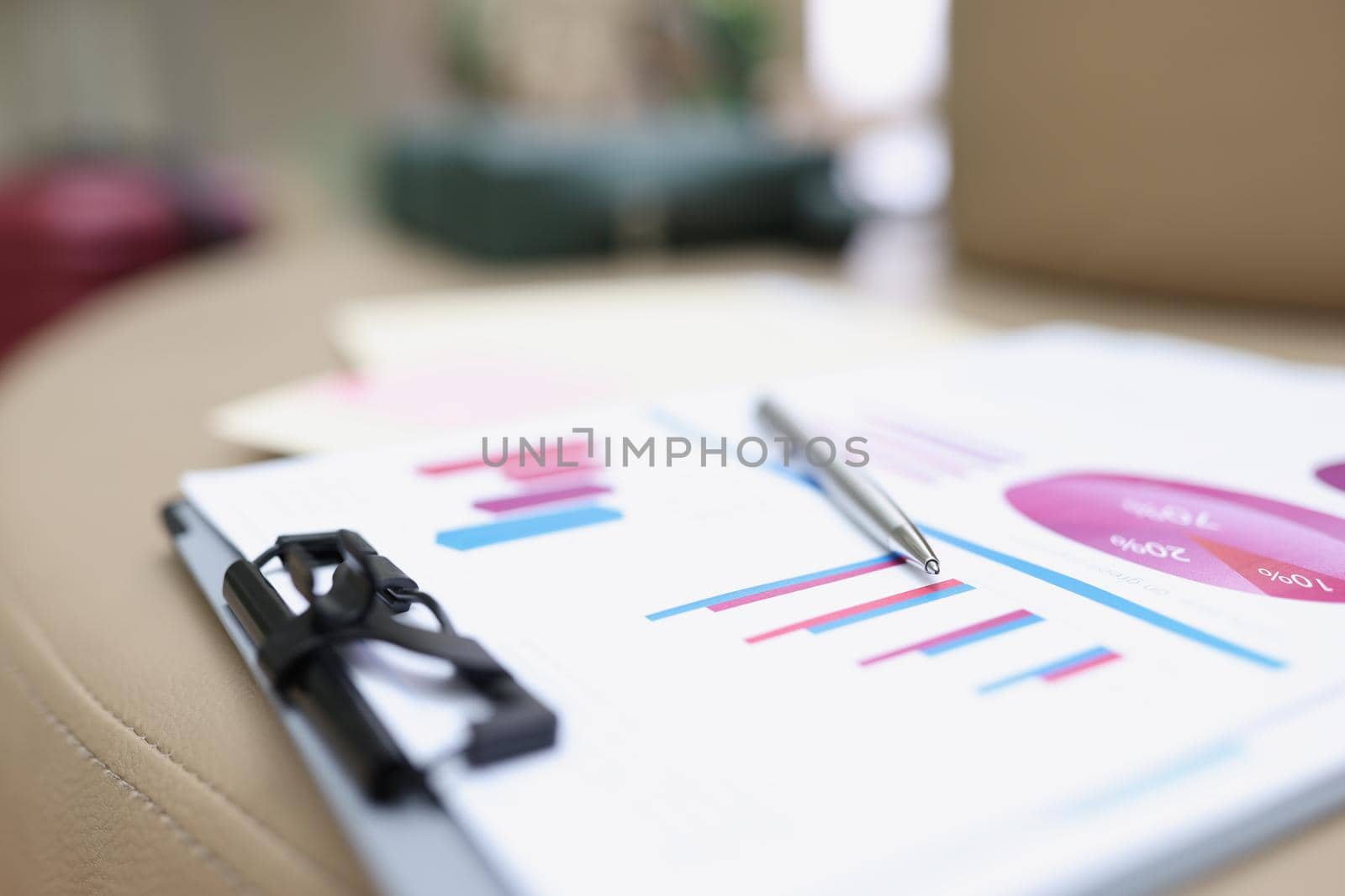 A folder with documents lies on a leather surface, close-up, blurry. Audit preparation, color chart and graph on paper