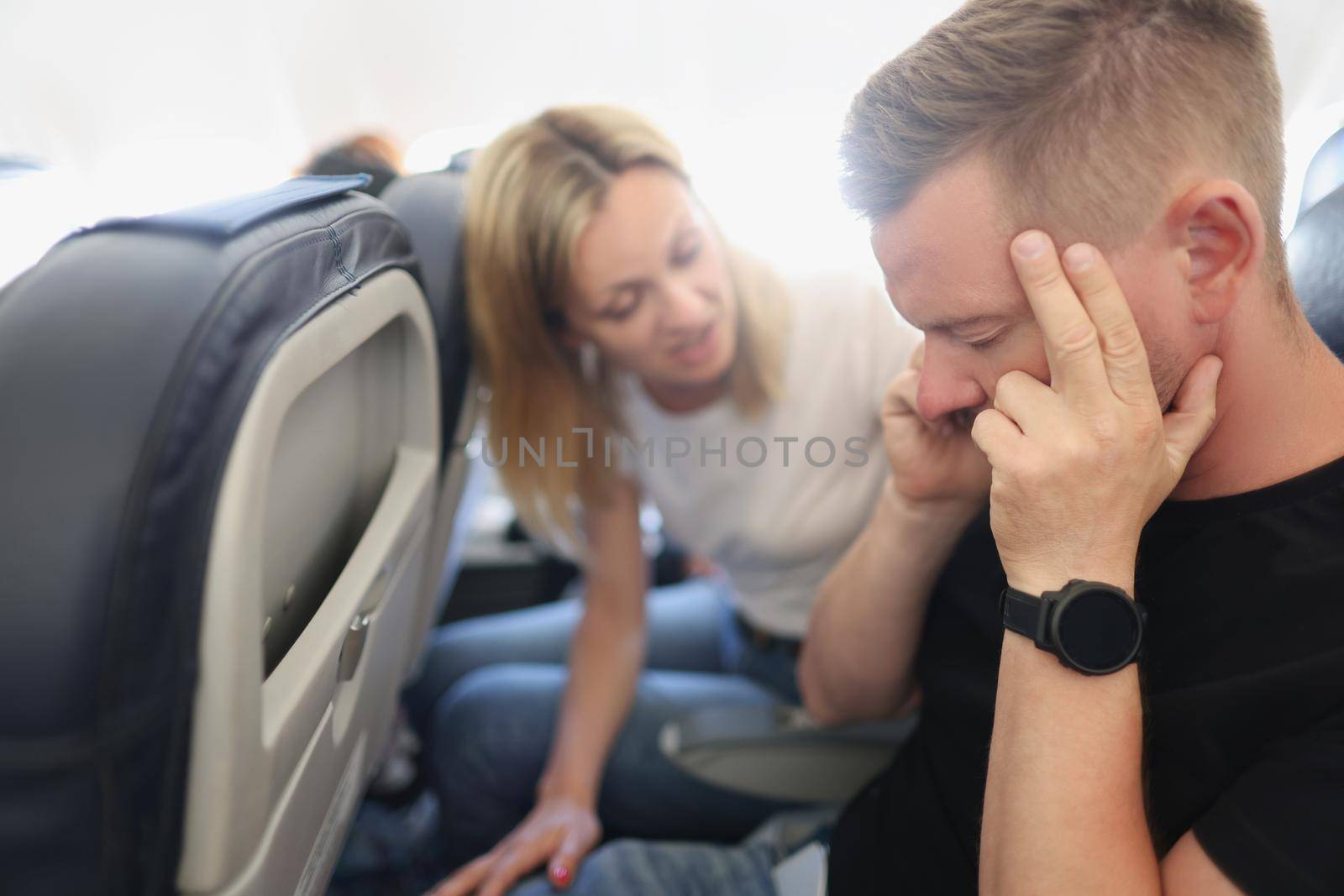 A man calms himself down in the aircraft cabin, aerophobia, close-up. The family travels, flight. Anxiety, turbulence