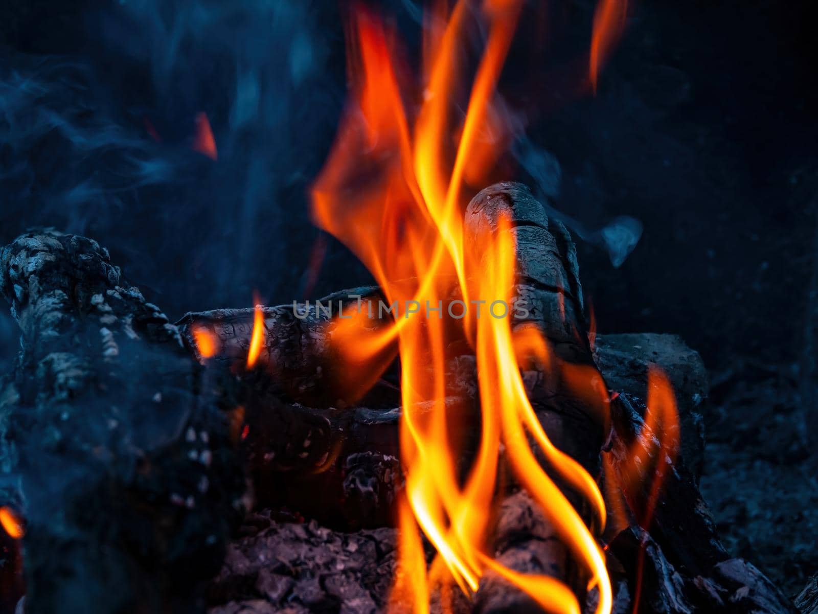 Orange flames of fire of a wood fire. The heat of a wood fire. Tourist place in nature in the forest. Cooking on the grill. Background image. Free space for text.
