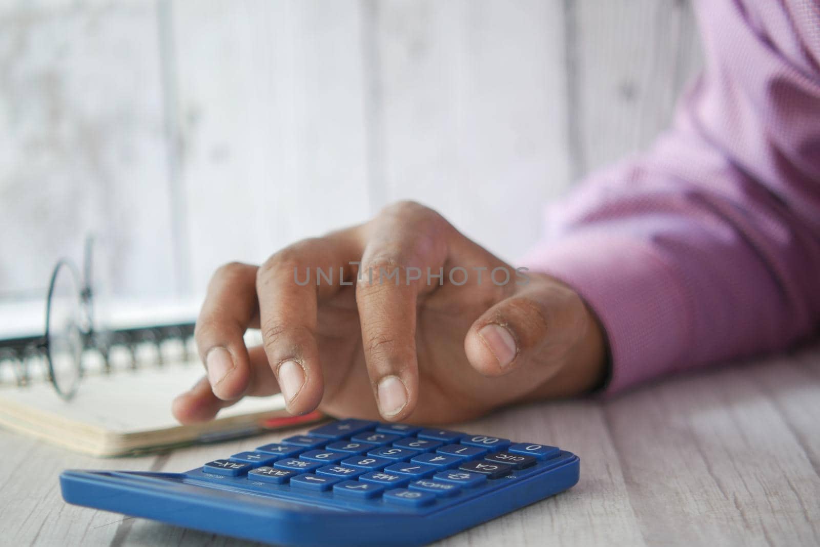 Close up of man hand using calculator.
