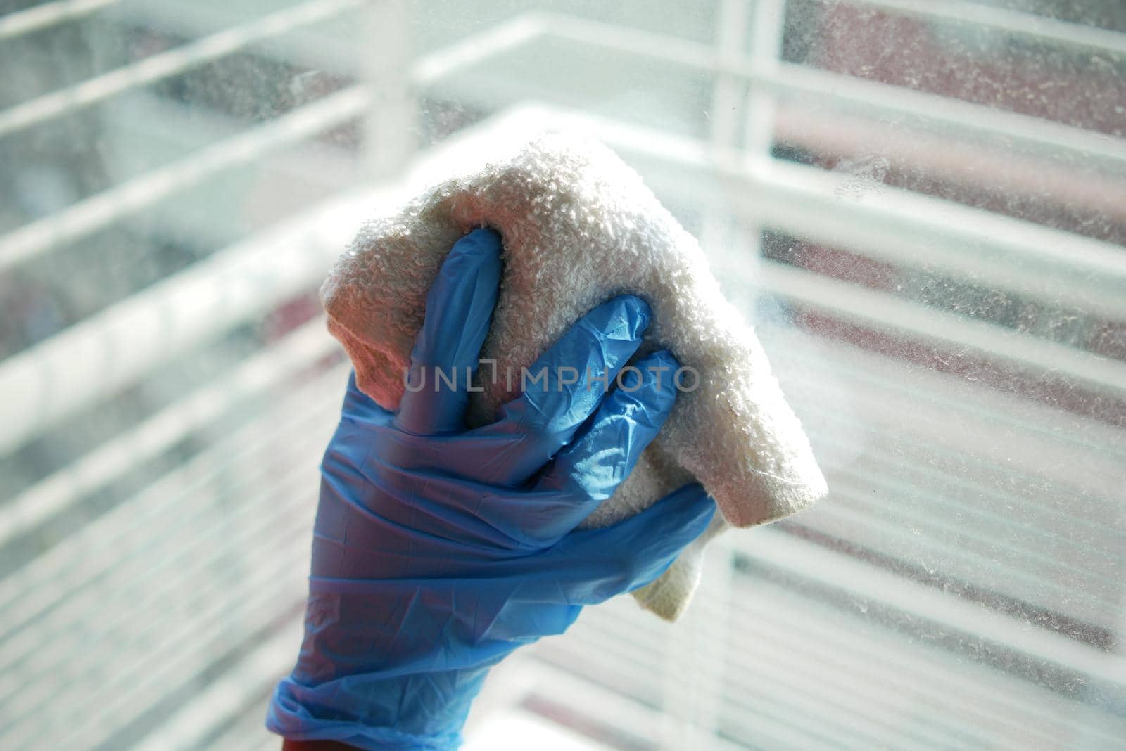close up of person hand in gloves cleaning window glass .