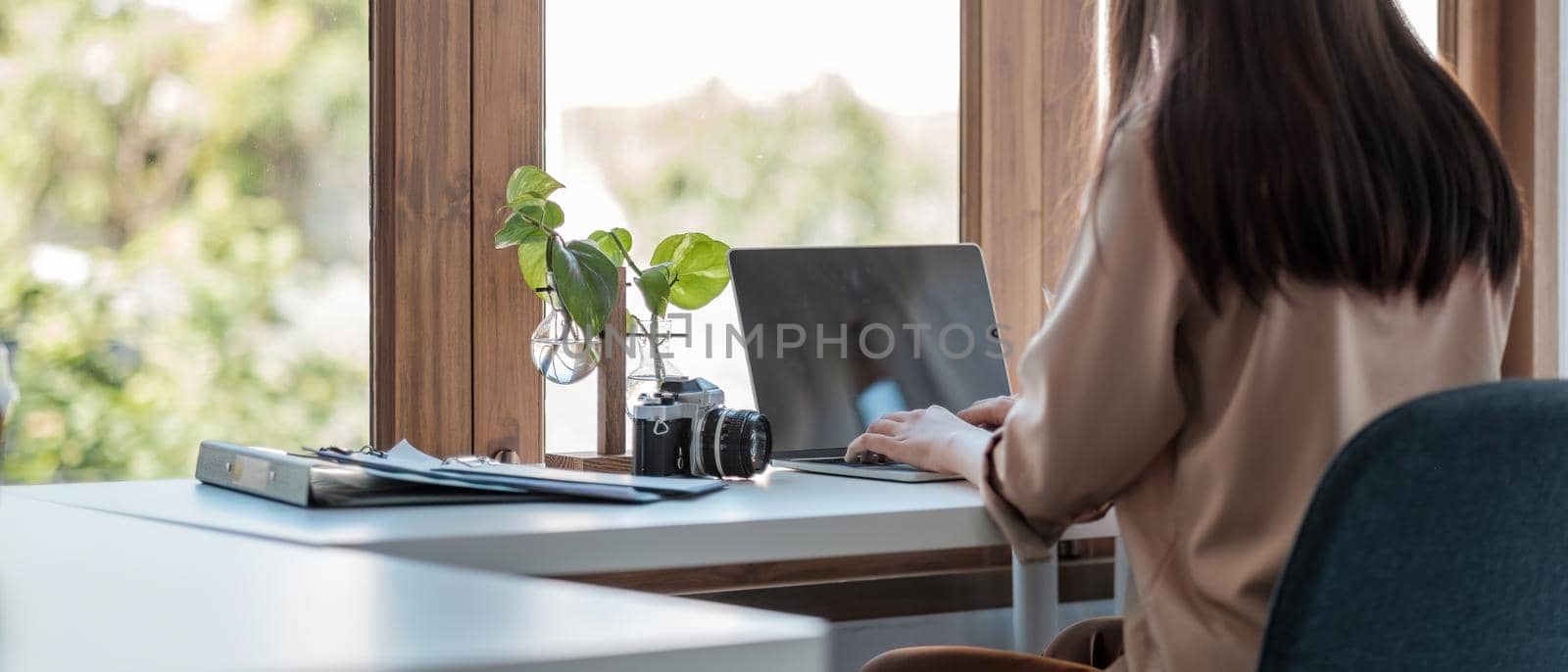 Back view of young asian businesswoman sitting on her workplace in the office. Young woman working for financial document data charts with laptop in the office